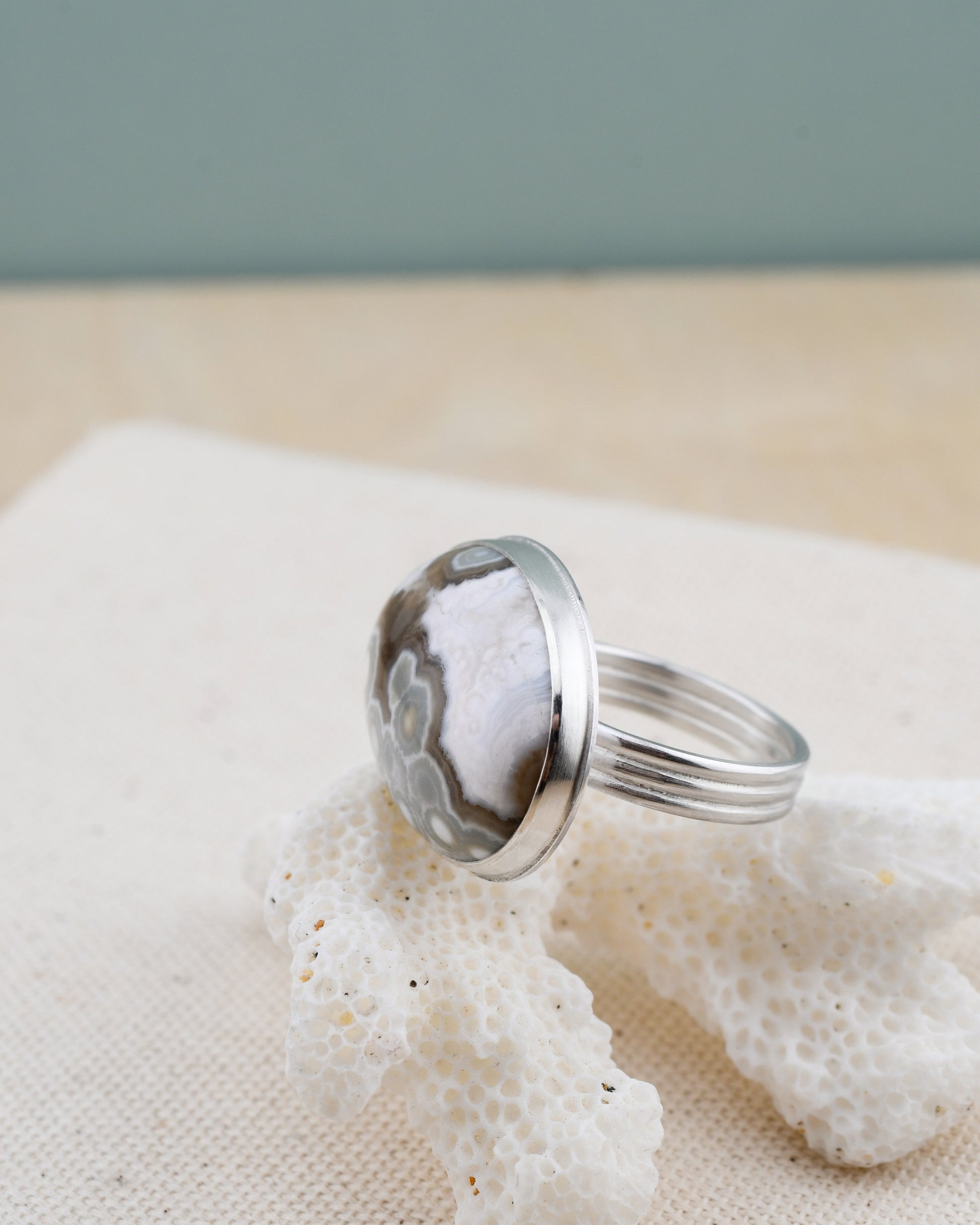 Silver ring with an oval ocean jasper on a piece of coral