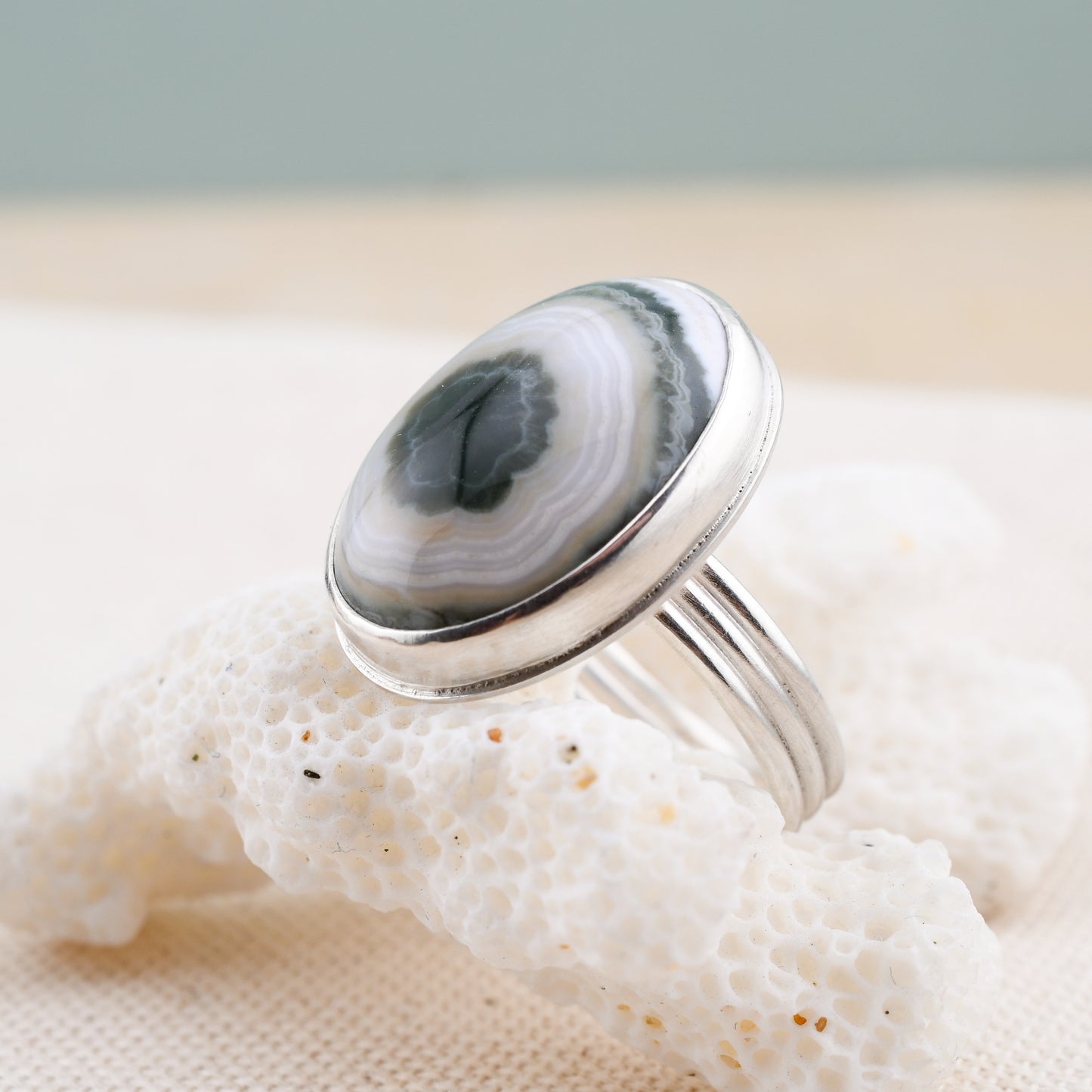 Silver ring with an oval ocean jasper on a textured surface