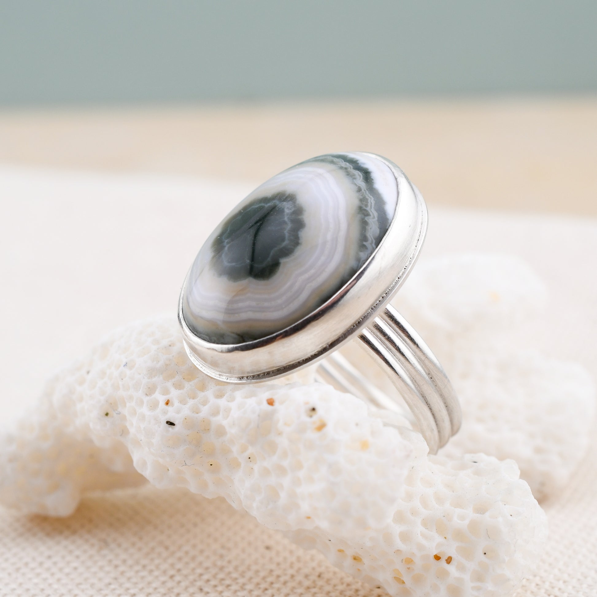 Silver ring with an oval ocean jasper on a textured surface