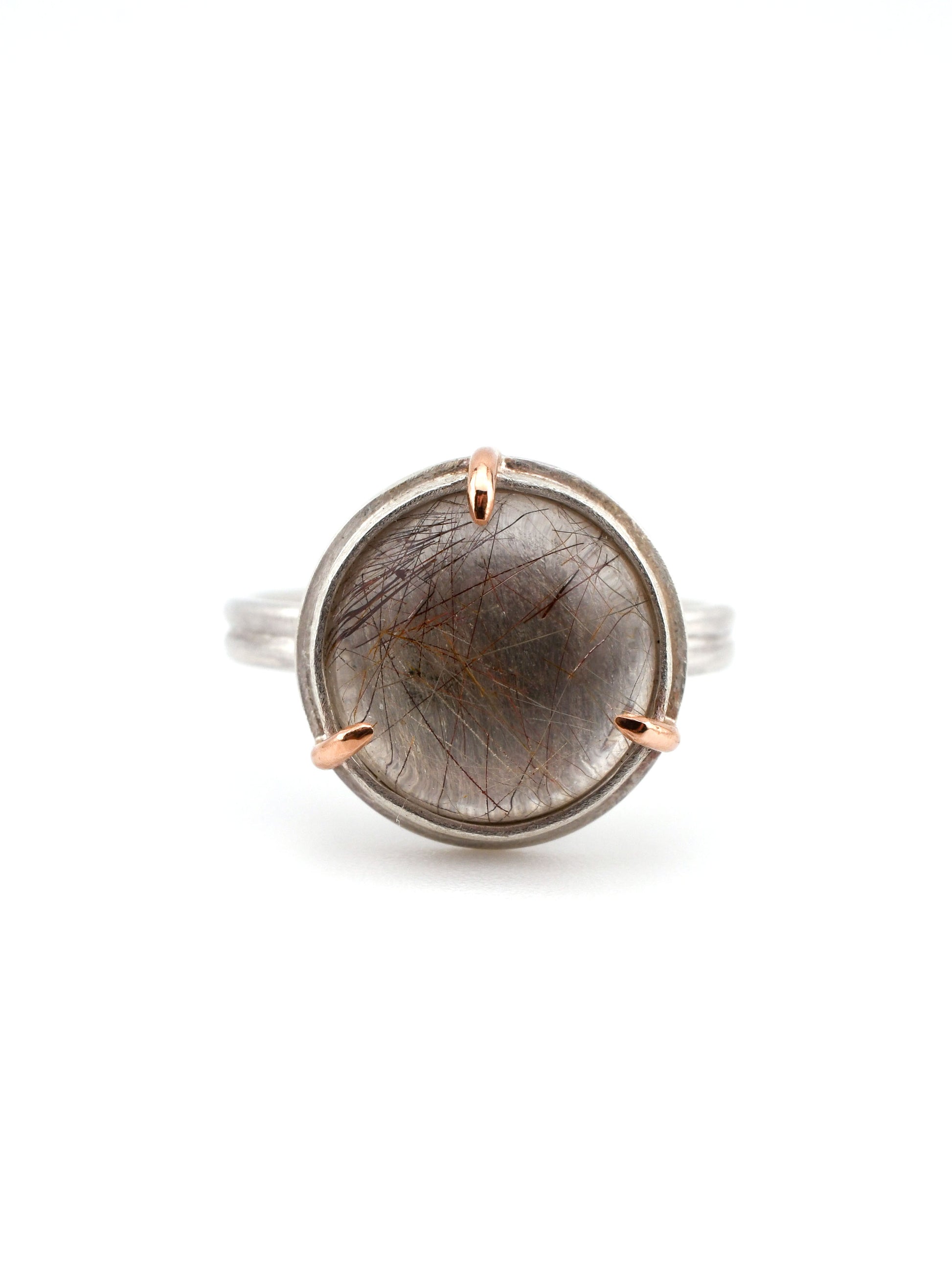 silver and rose gold ring with round red rutilated quartz on a white background