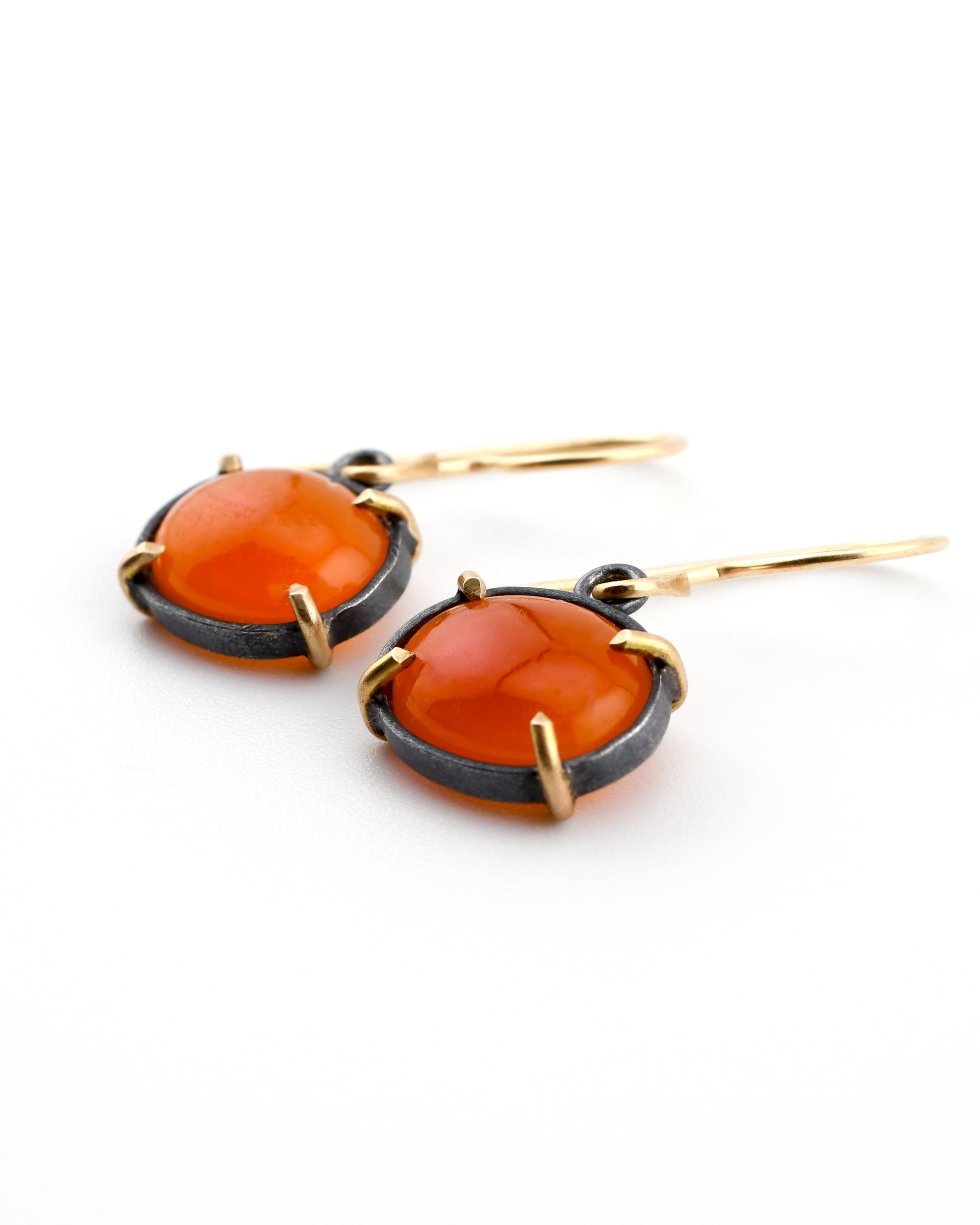 Pair of earrings with orange stones and gold accents on a white background
