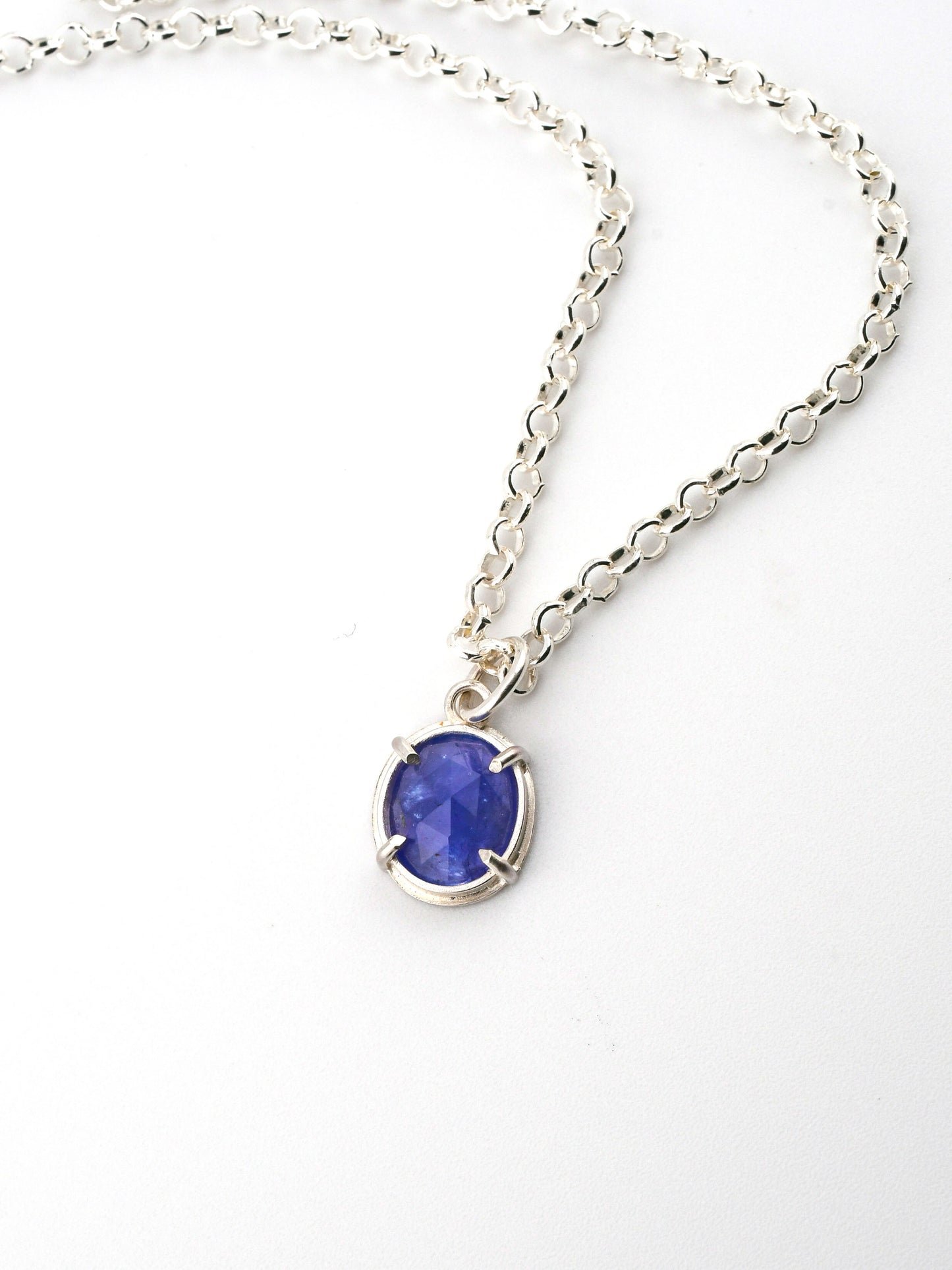 Silver necklace with a blue gemstone pendant on a white background