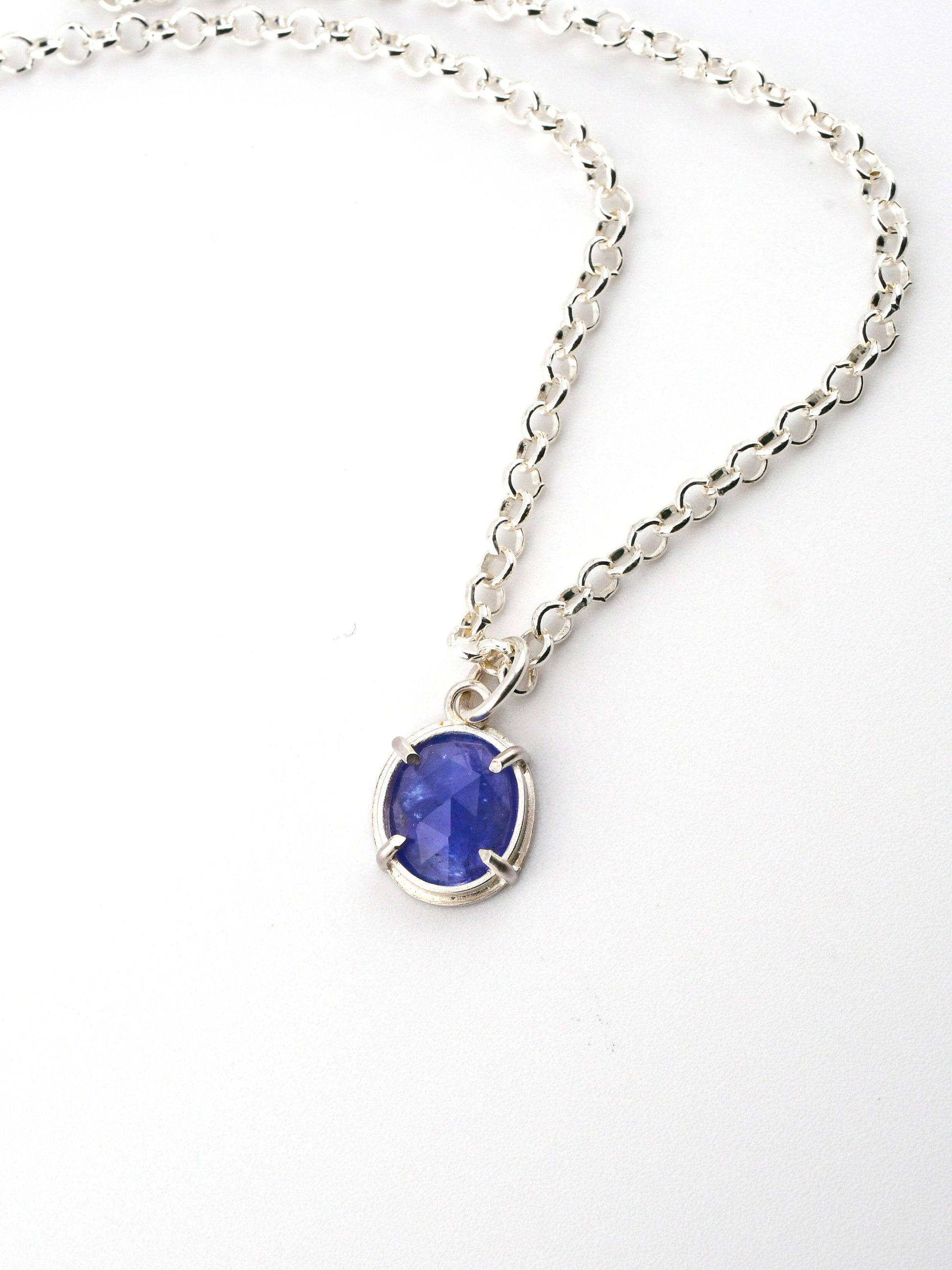 Silver necklace with a blue gemstone pendant on a white background