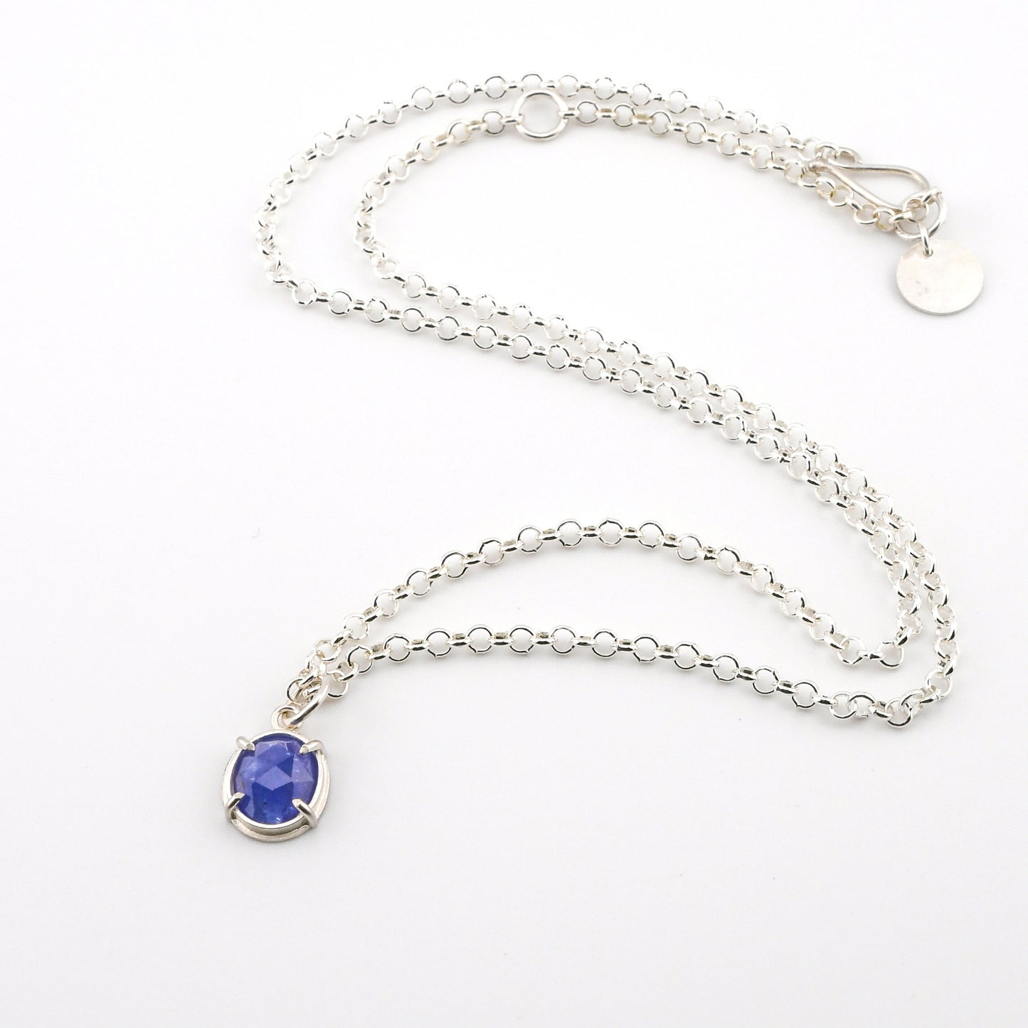 Silver necklace with a blue gemstone pendant on a white background