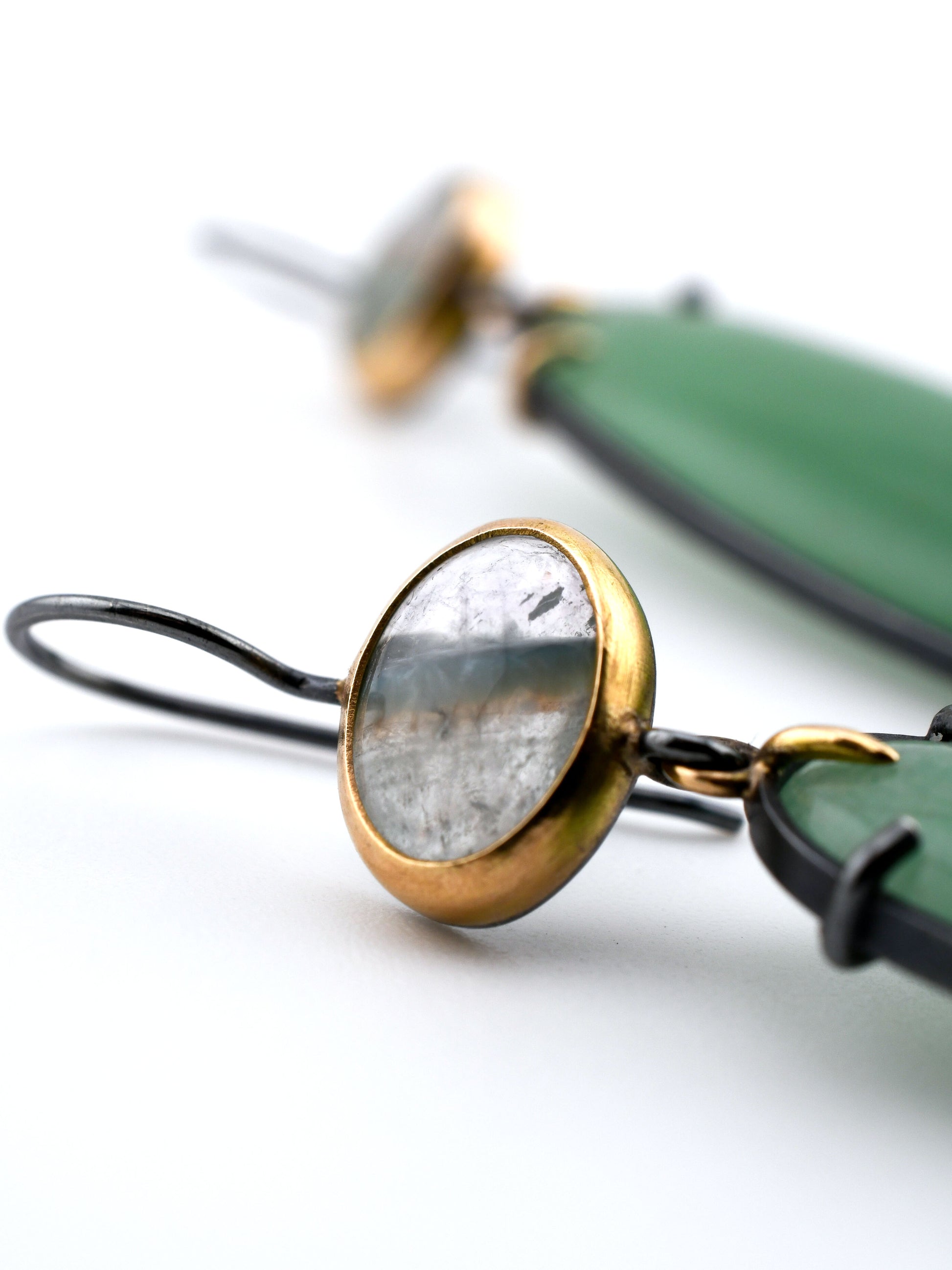Close-up of a gold and green earring on a white background