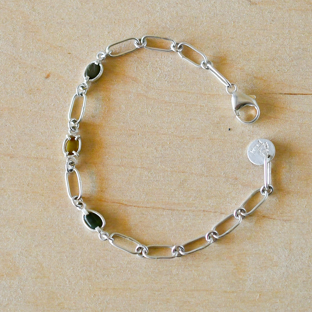 Silver chain bracelet with beach stones on a wooden surface