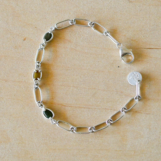Silver chain bracelet with beach stones on a wooden surface