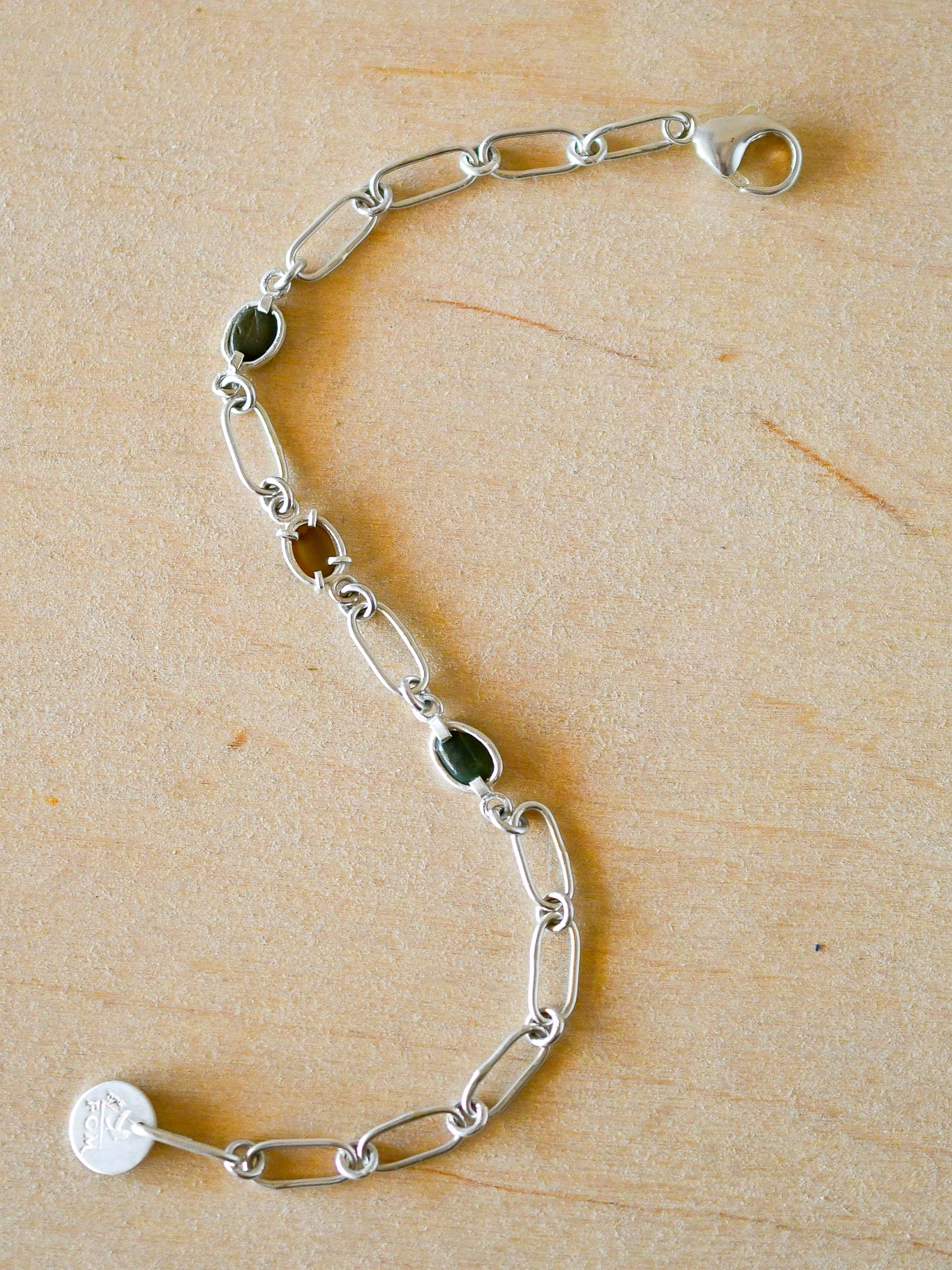Silver bracelet with green stones on a wooden surface