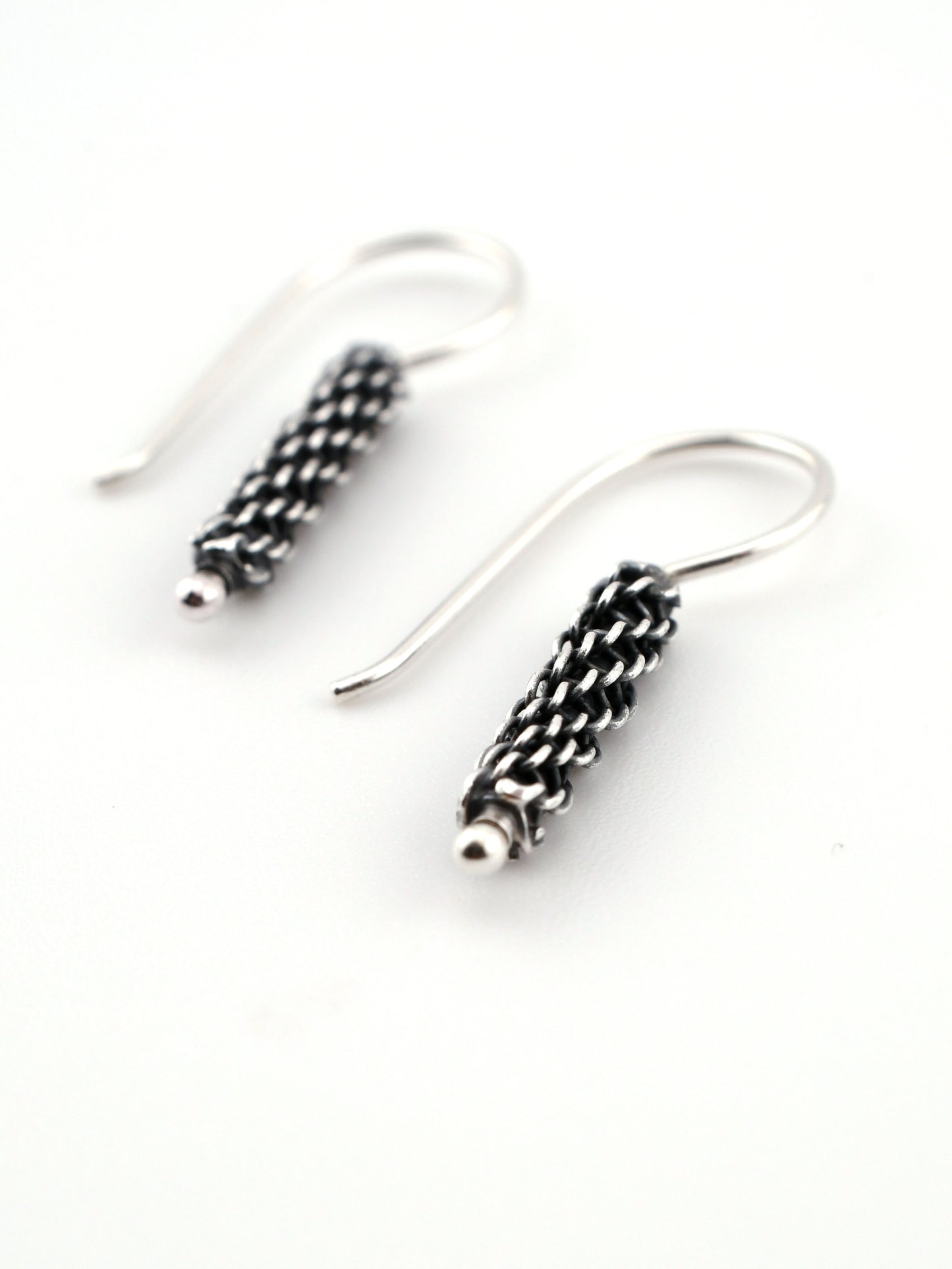 Silver earrings with intricate designs on a white background