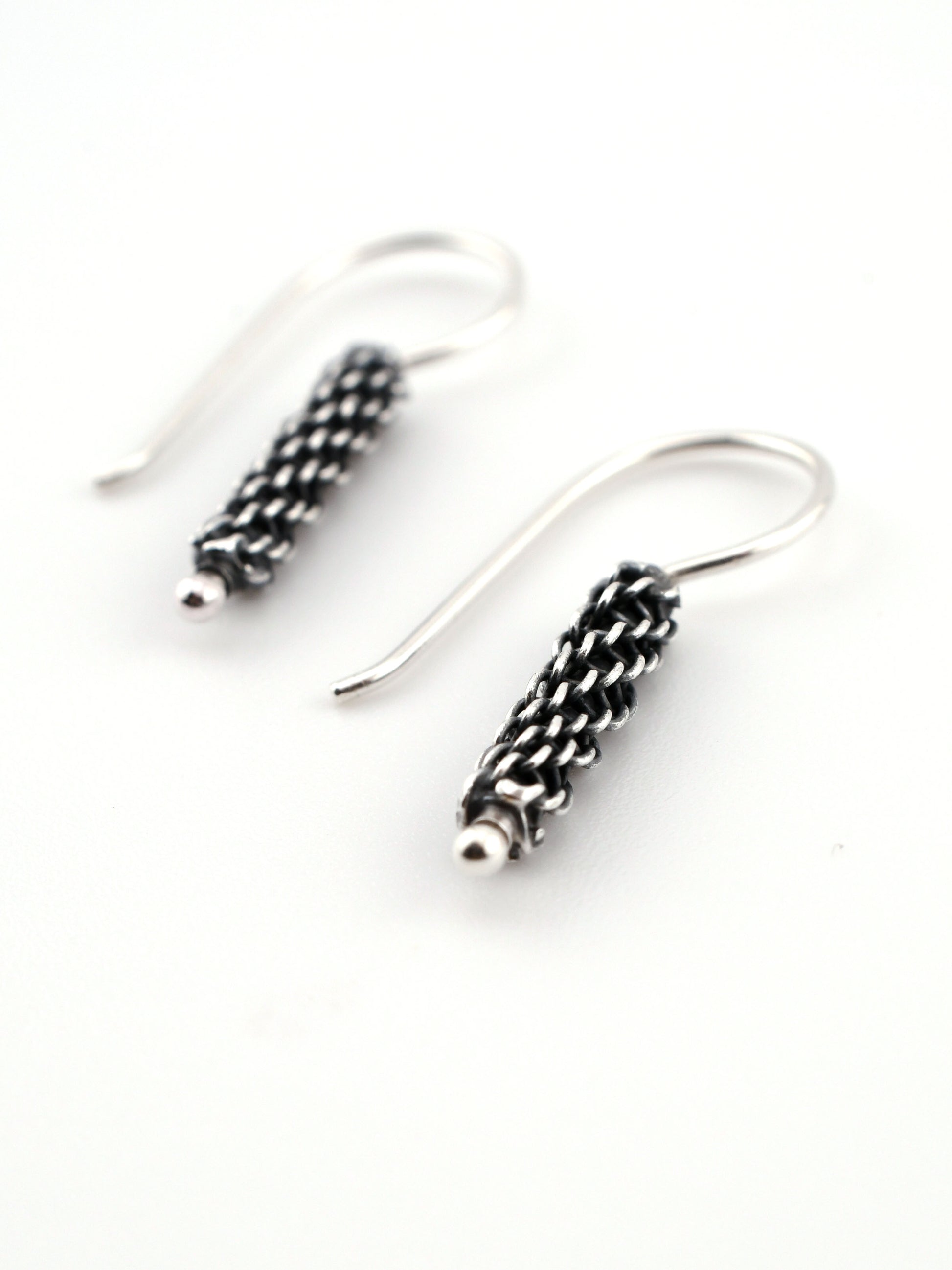 Silver earrings with intricate designs on a white background