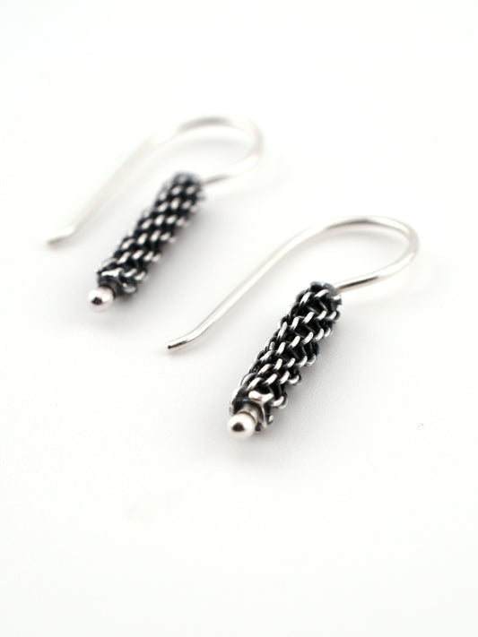 Silver earrings with intricate designs on a white background