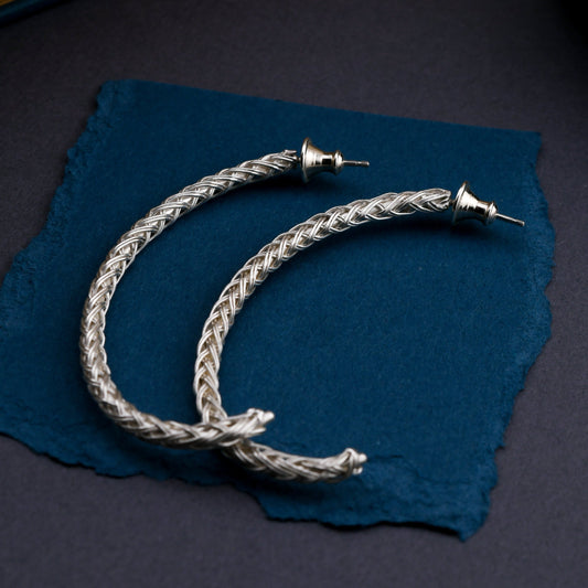 Silver braided earring on a textured  blue background