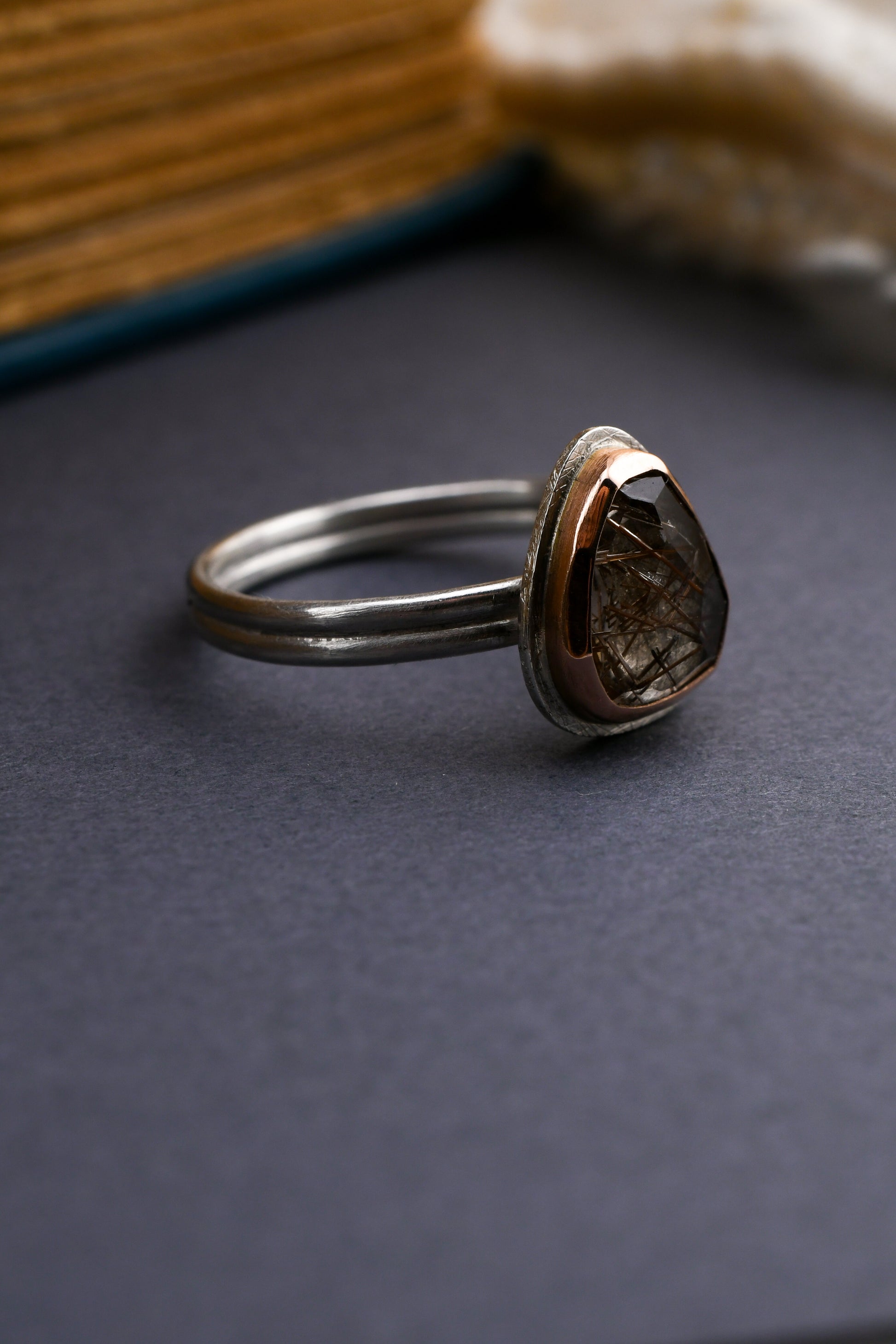 Silver ring with a teardrop-shaped gemstone on a dark surface