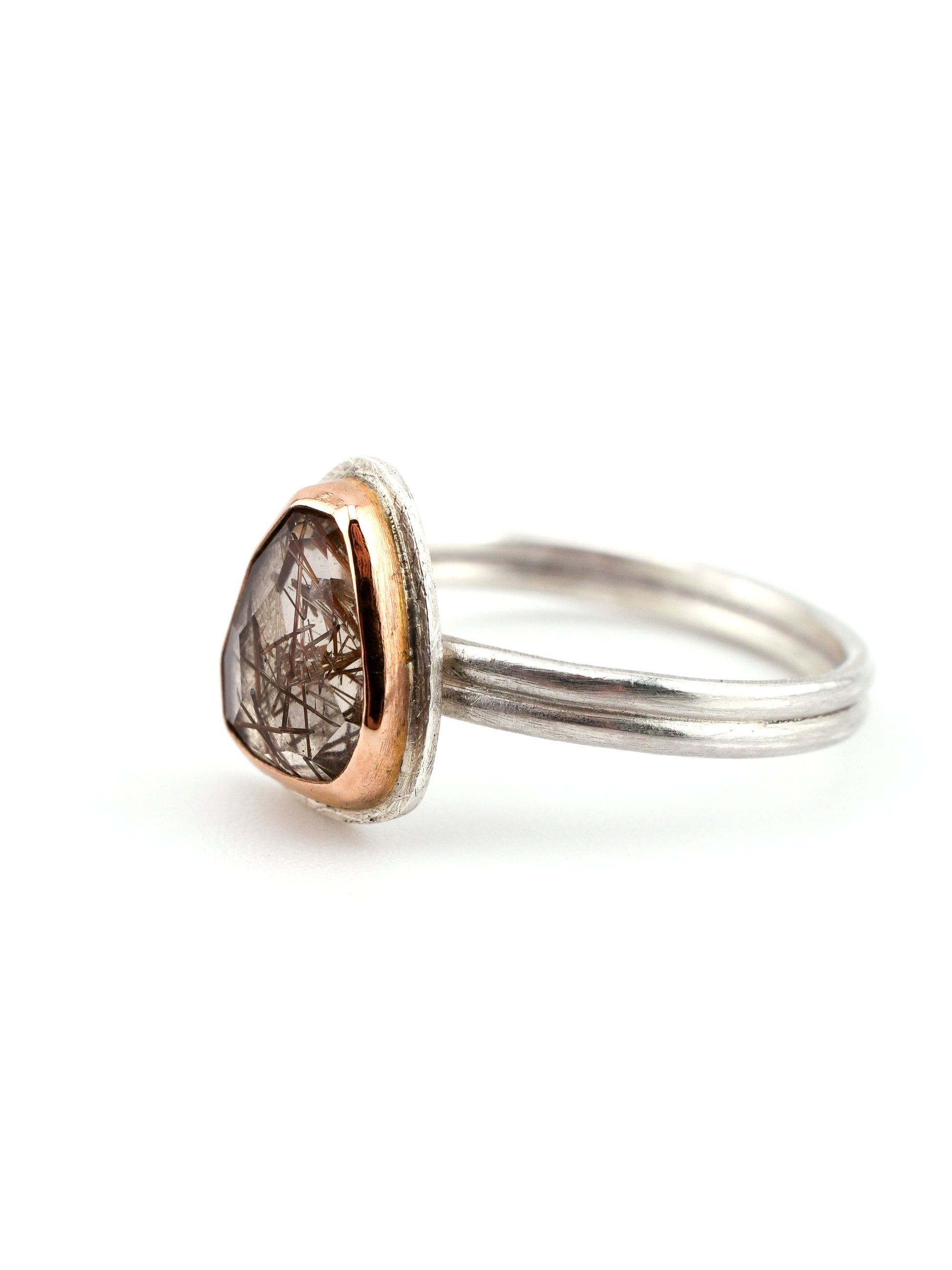 Silver ring with a rose gold accent and gemstone on a white background