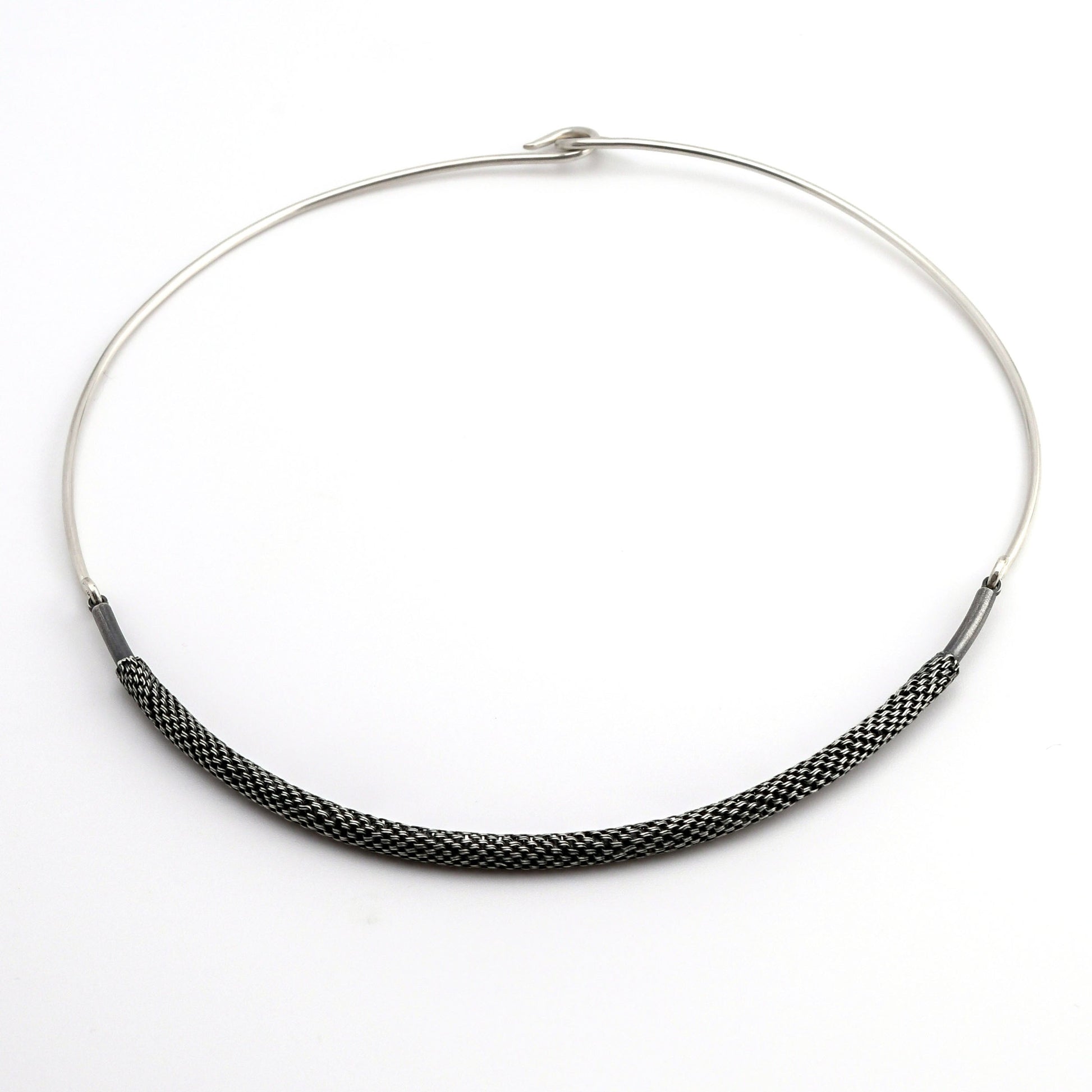 Silver torque necklace with woven silver front piece on a white background