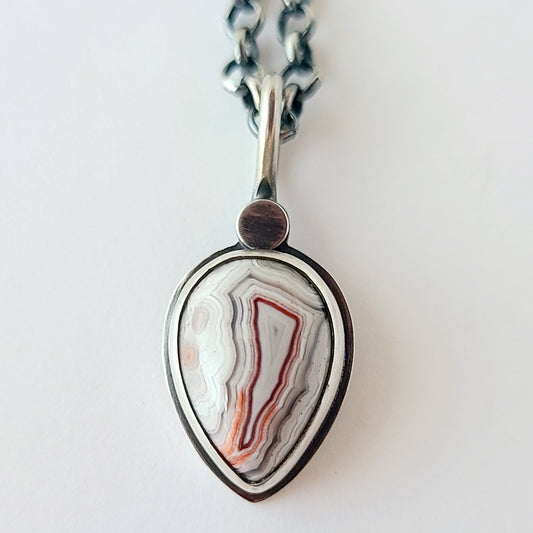 crazy lace teardrop pendant with white red and gray patterns and a silver circle at the top shown on a white background