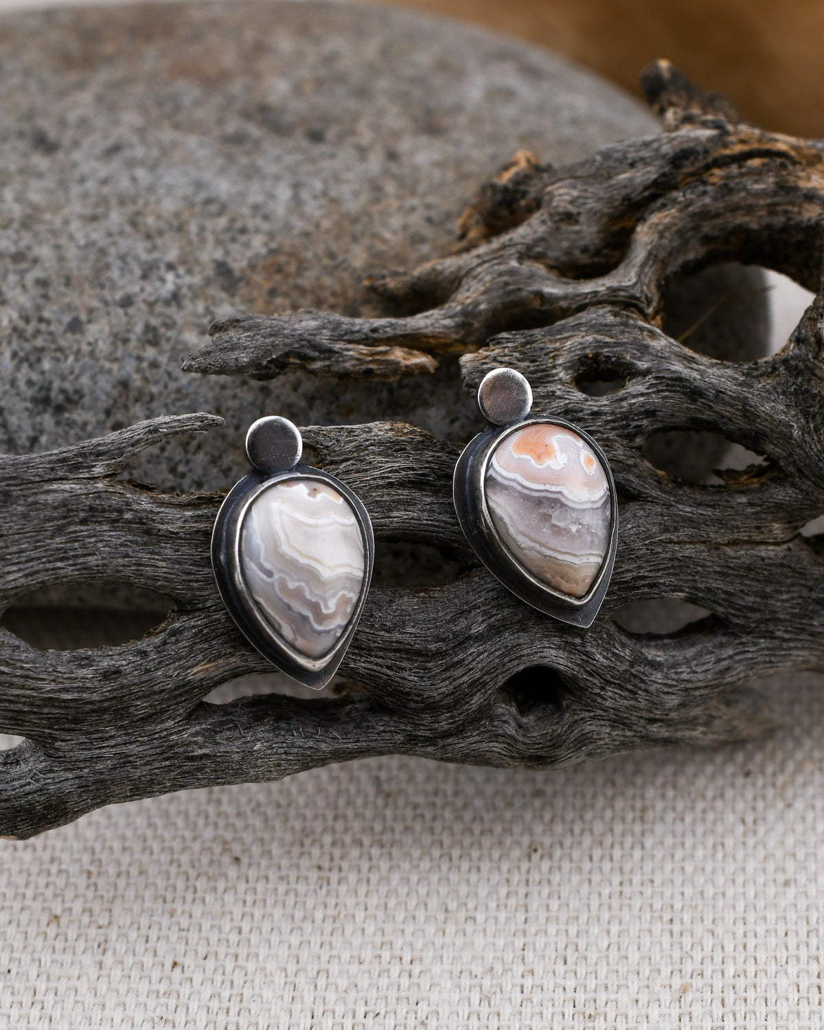 Sterling silver teardrop stud earrings with peach and cream crazy lace agate with crystal pockets displayed on cactus wood and linen