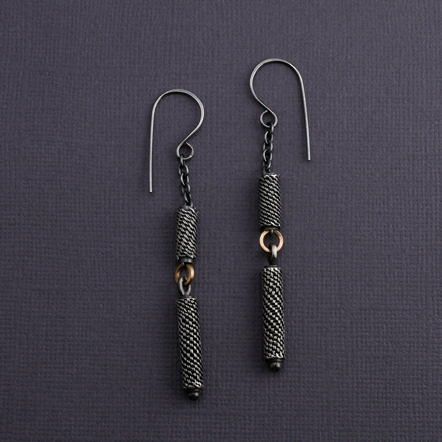 Pair of silver earrings with textured beads on a dark gray background