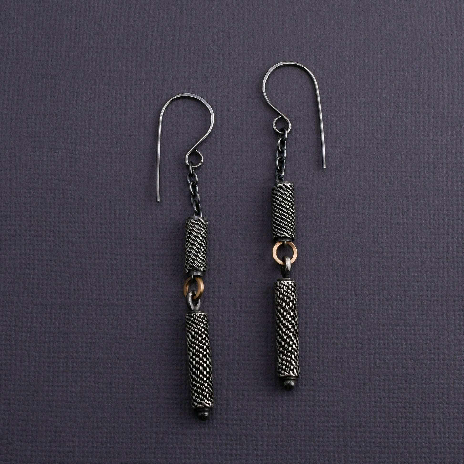 Pair of silver earrings with textured beads on a dark gray background