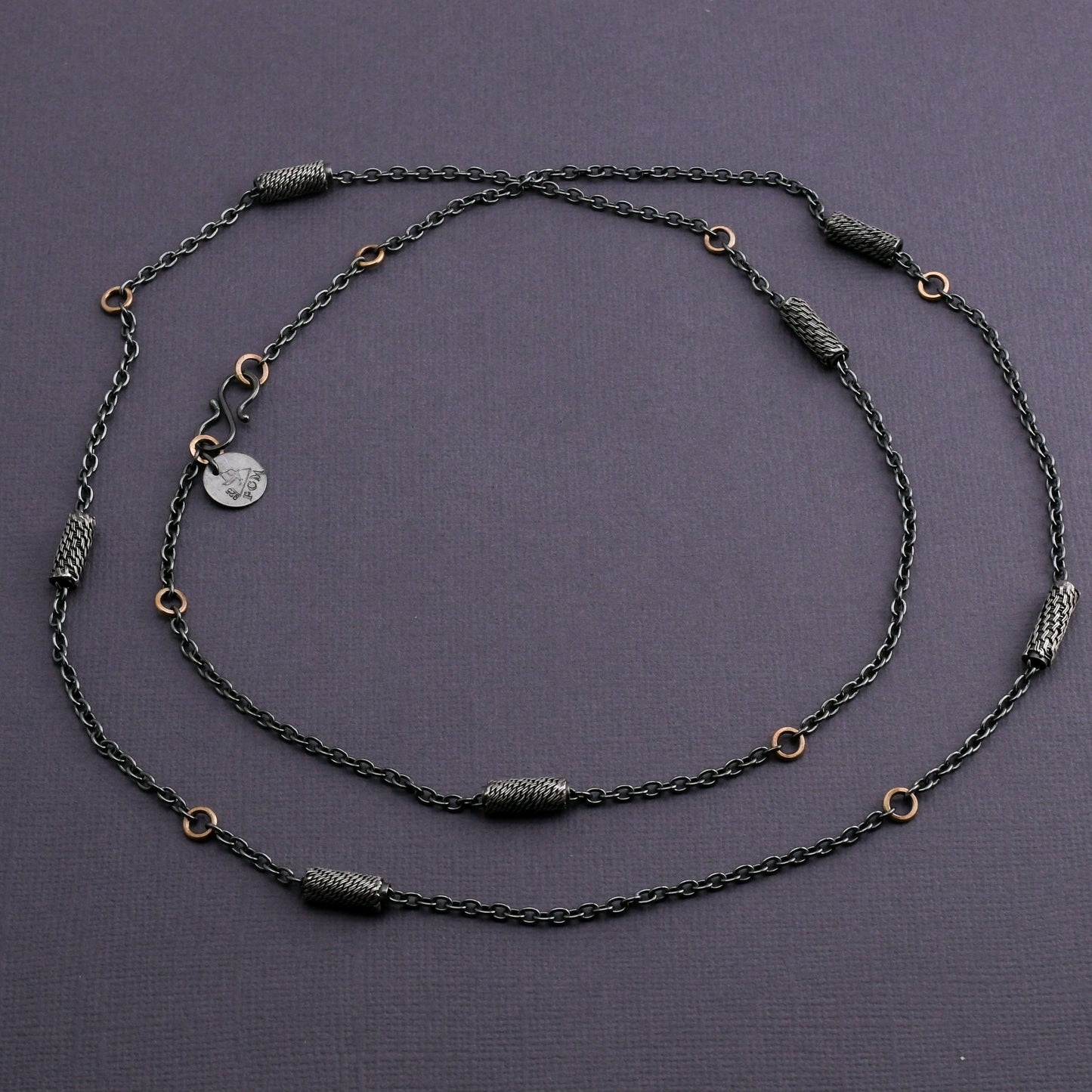 Black silver chain necklace with woven silver beads and 14k gold links on a dark gray background