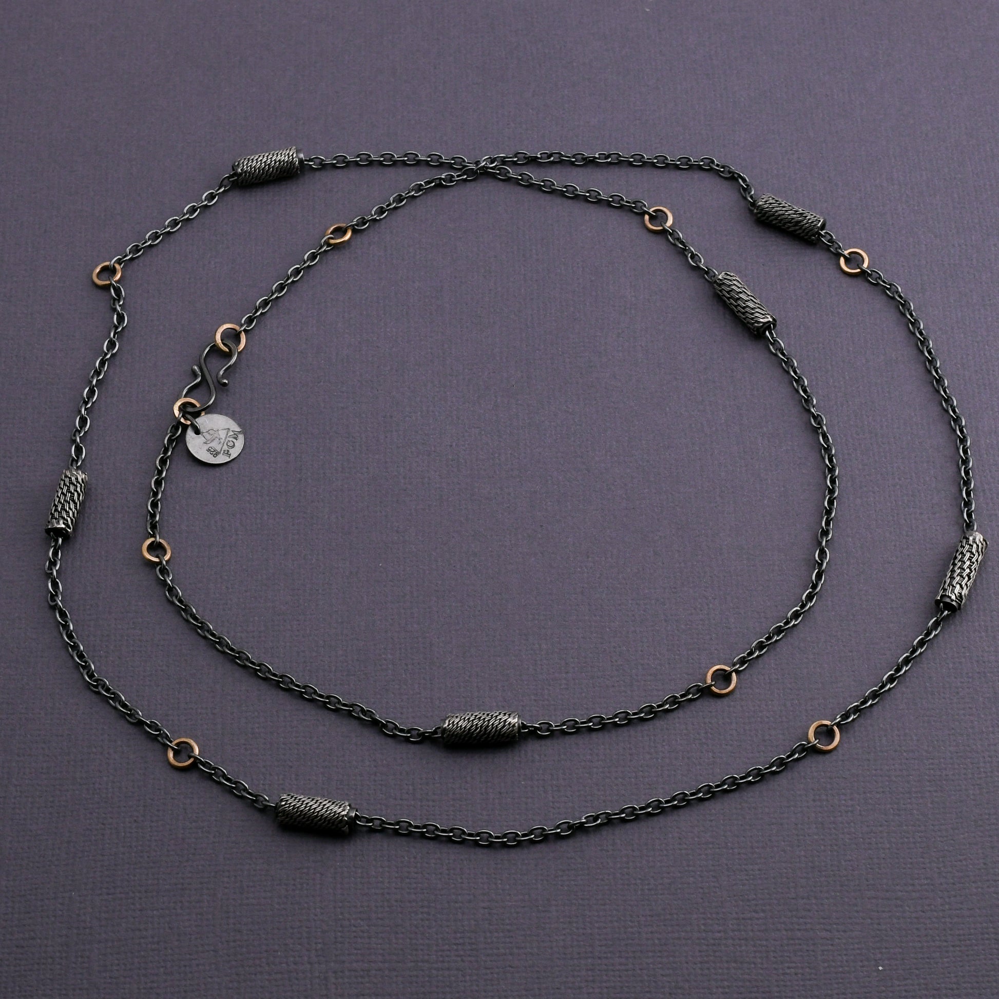 Black silver chain necklace with woven silver beads and 14k gold links on a dark gray background