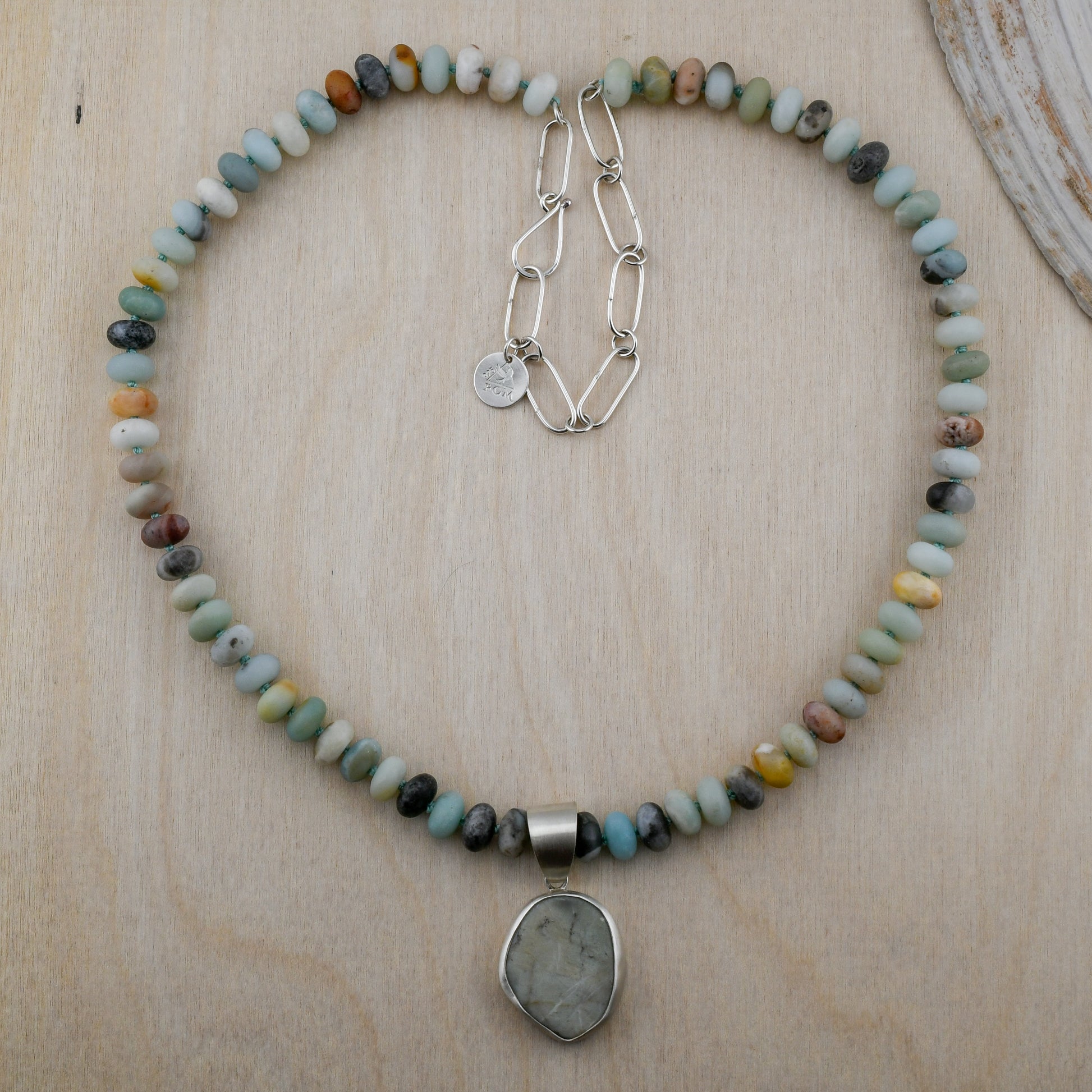 Necklace with multicolored beads and a pendant on a wooden surface