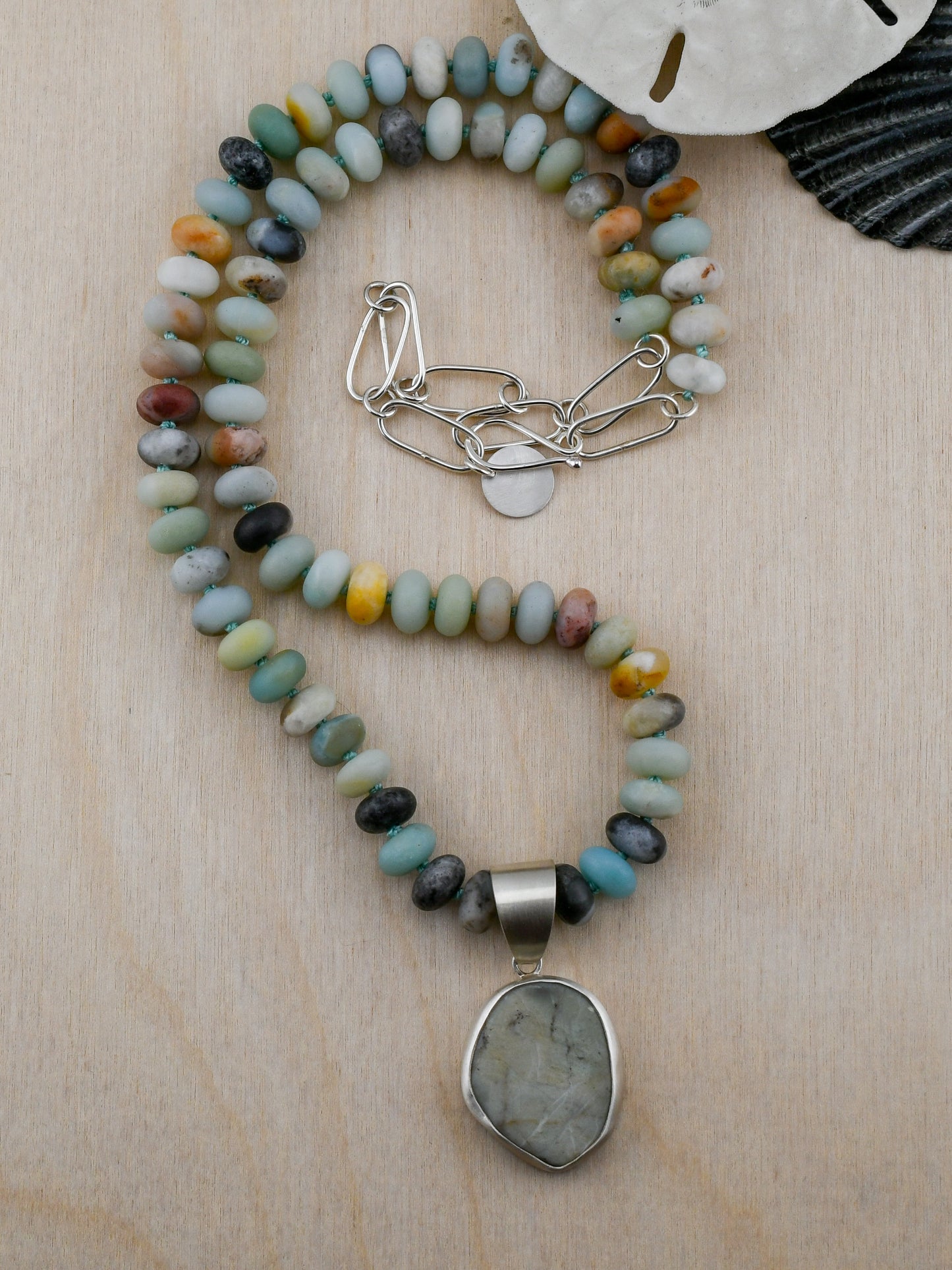 Necklace with multicolored beads and a large pendant on a wooden surface