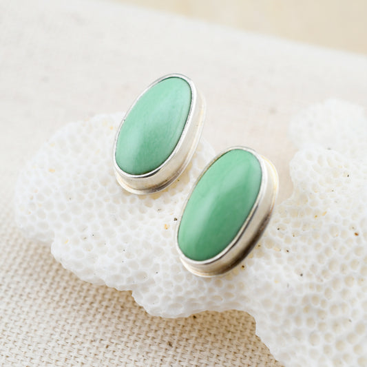 oval mint green variscite and silver stud earrings on white coral with a textured background