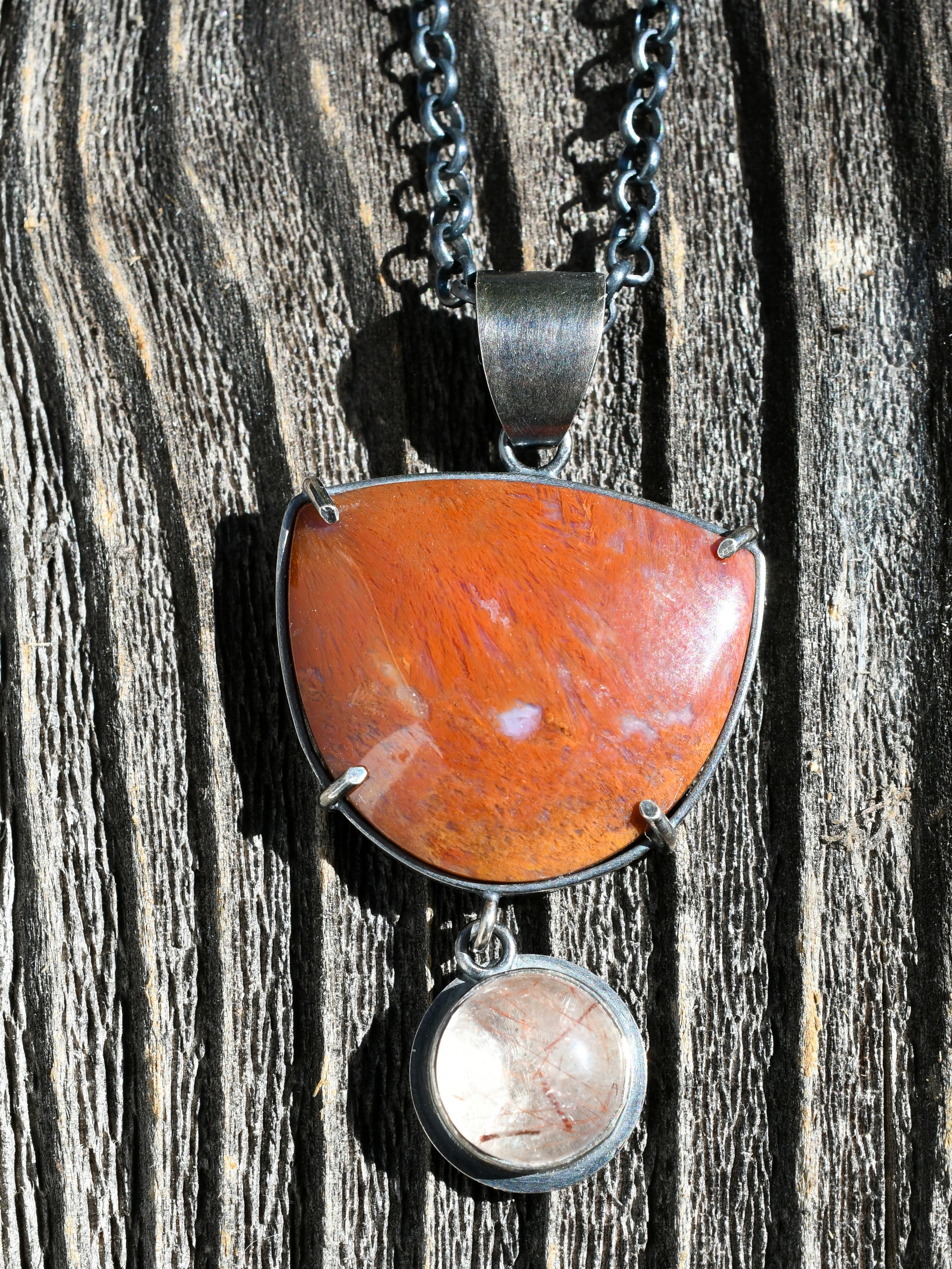 Necklace with a large red and orange stone pendant on a wooden surface