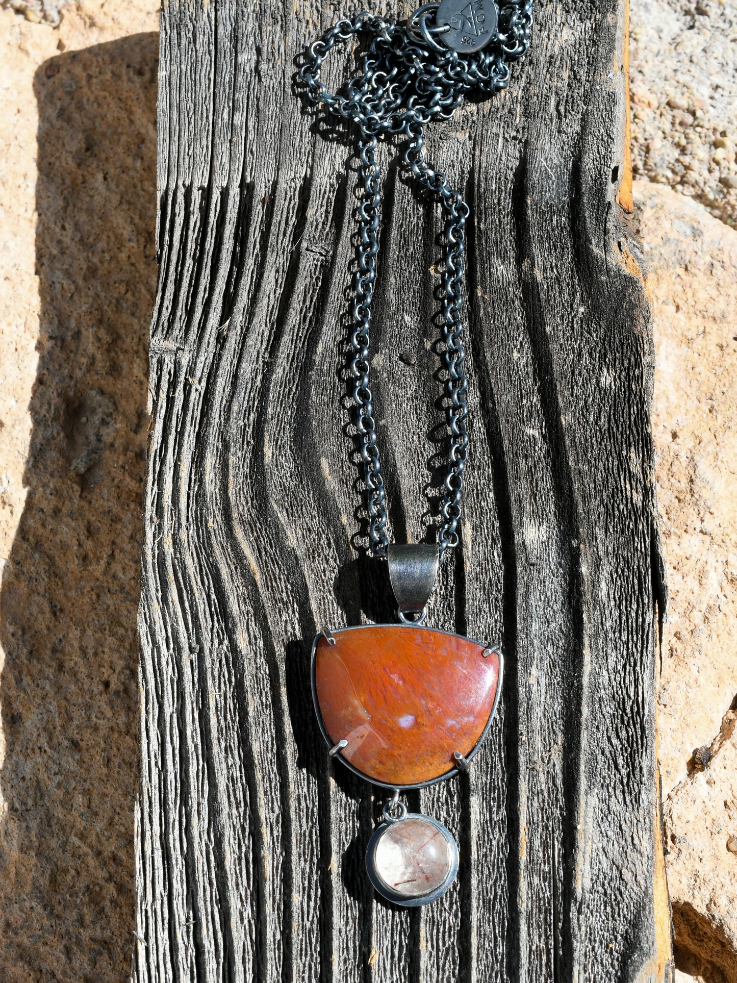 Necklace with a red stone pendant on a wooden surface
