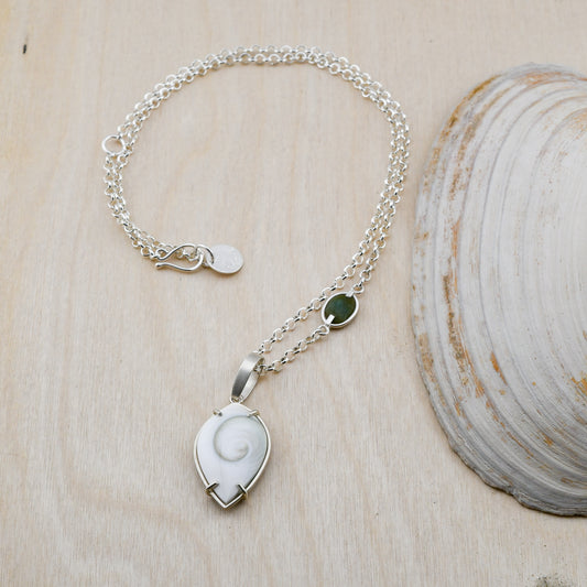 Silver necklace with green beach stone and Spiral Shiva shell pendant on a neutral background