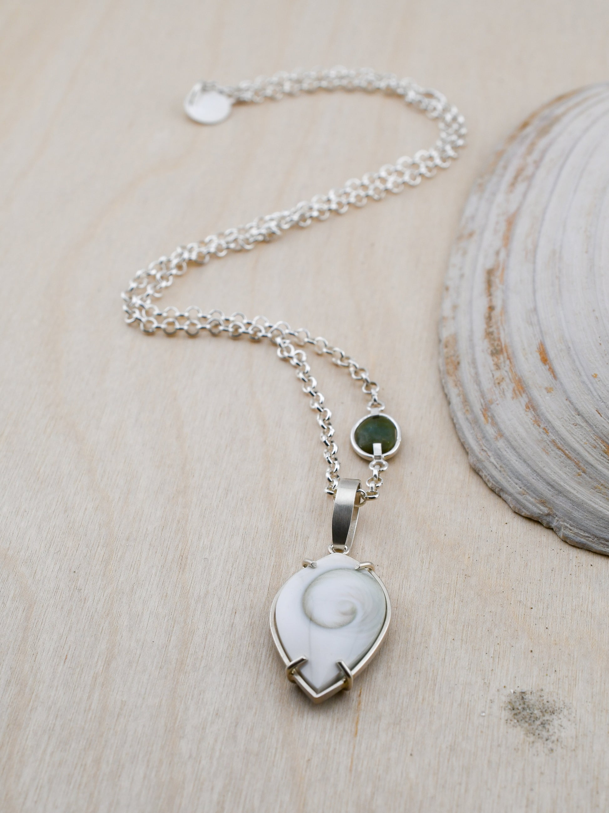 Necklace with a white shell pendant on a wooden surface