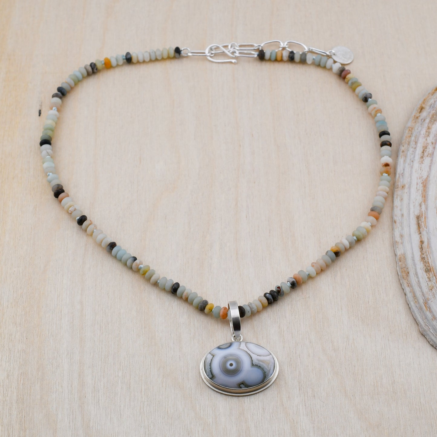 Amazonite beaded necklace with Ocean Jasper pendant on a pale wood background
