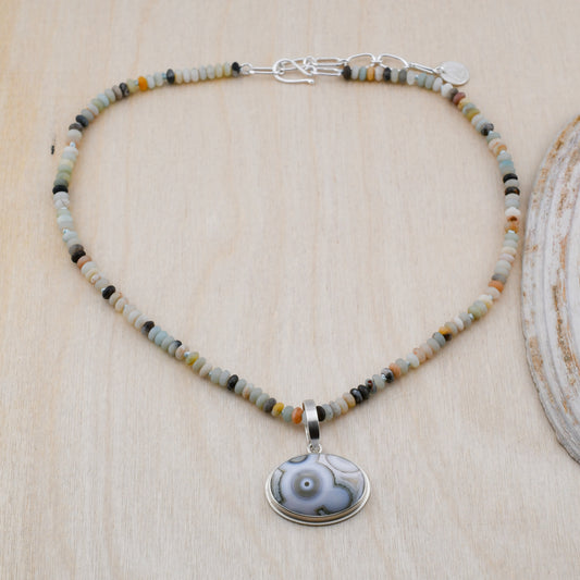 Amazonite beaded necklace with Ocean Jasper pendant on a pale wood background