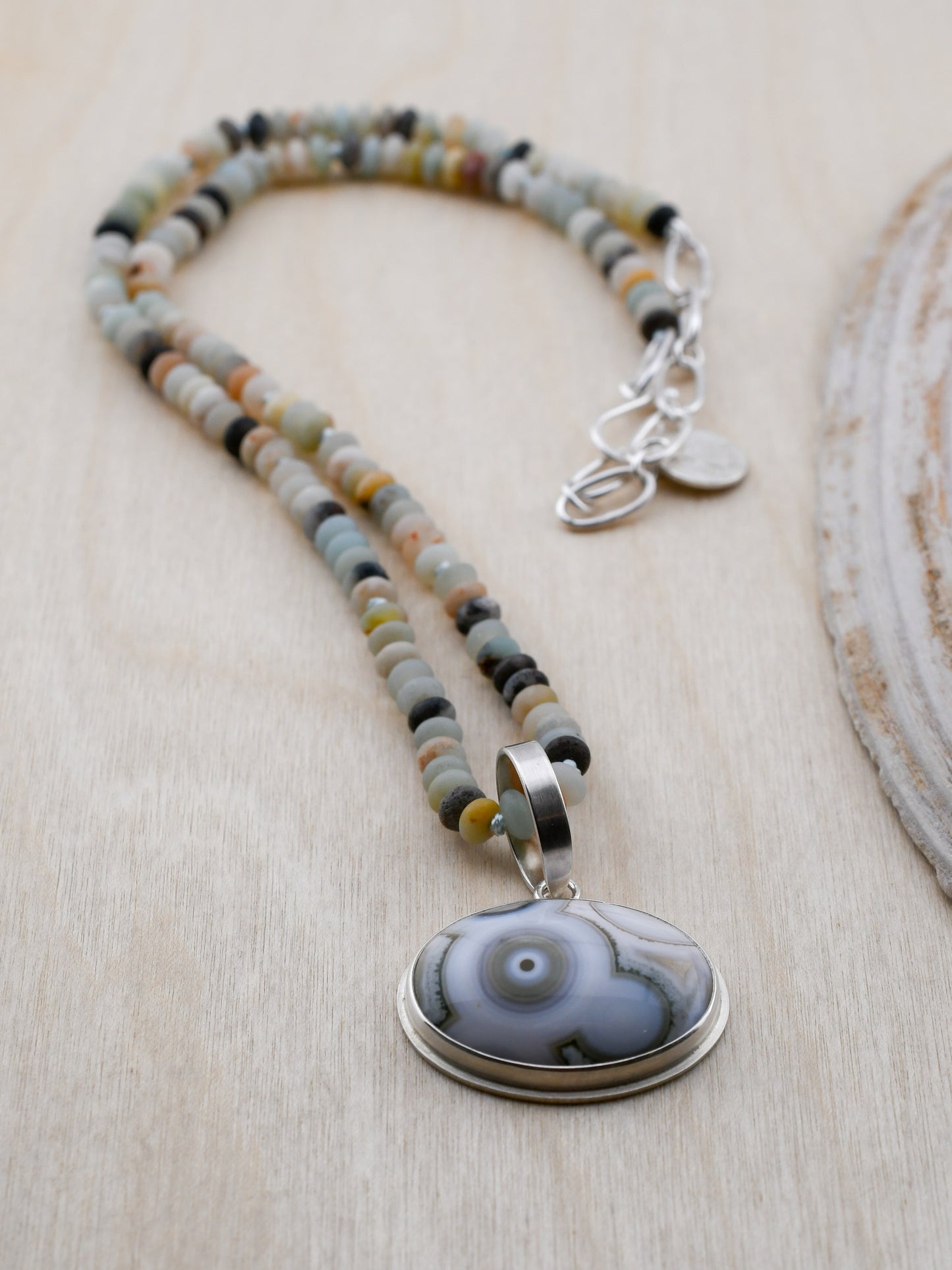 Necklace with beaded chain and ocean jasper pendant on a wooden surface