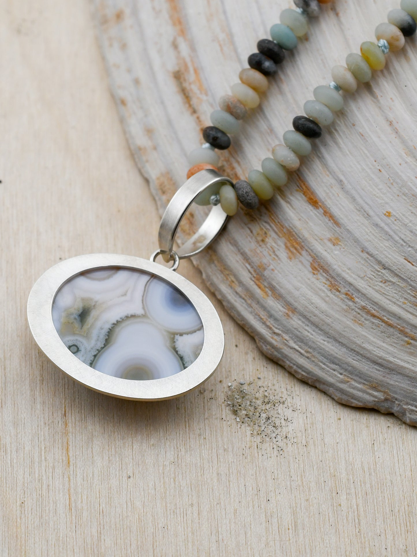 closeup of backside of ocean jasper pendant necklace on a neutral background