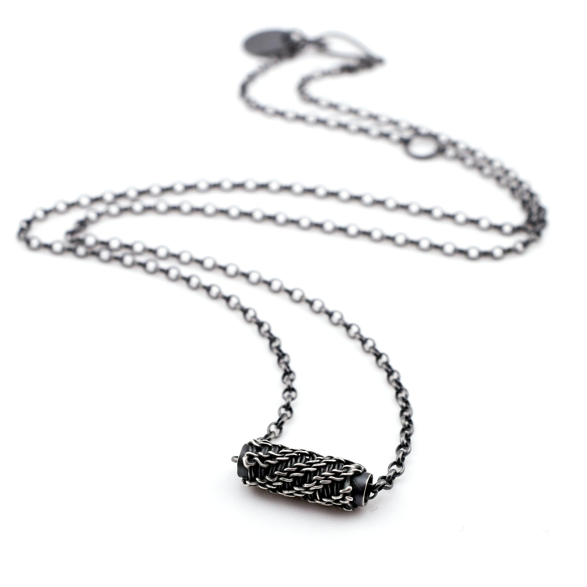 Silver necklace with a woven sliding bead pendant on a white background