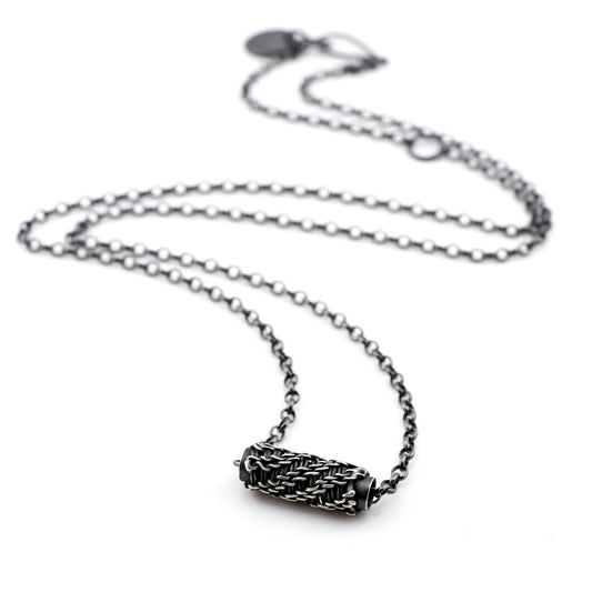 Silver necklace with a woven sliding bead pendant on a white background