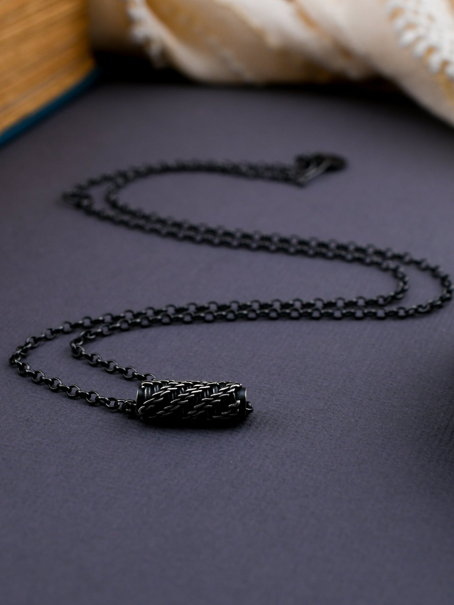 Black woven bead necklace on a textured surface