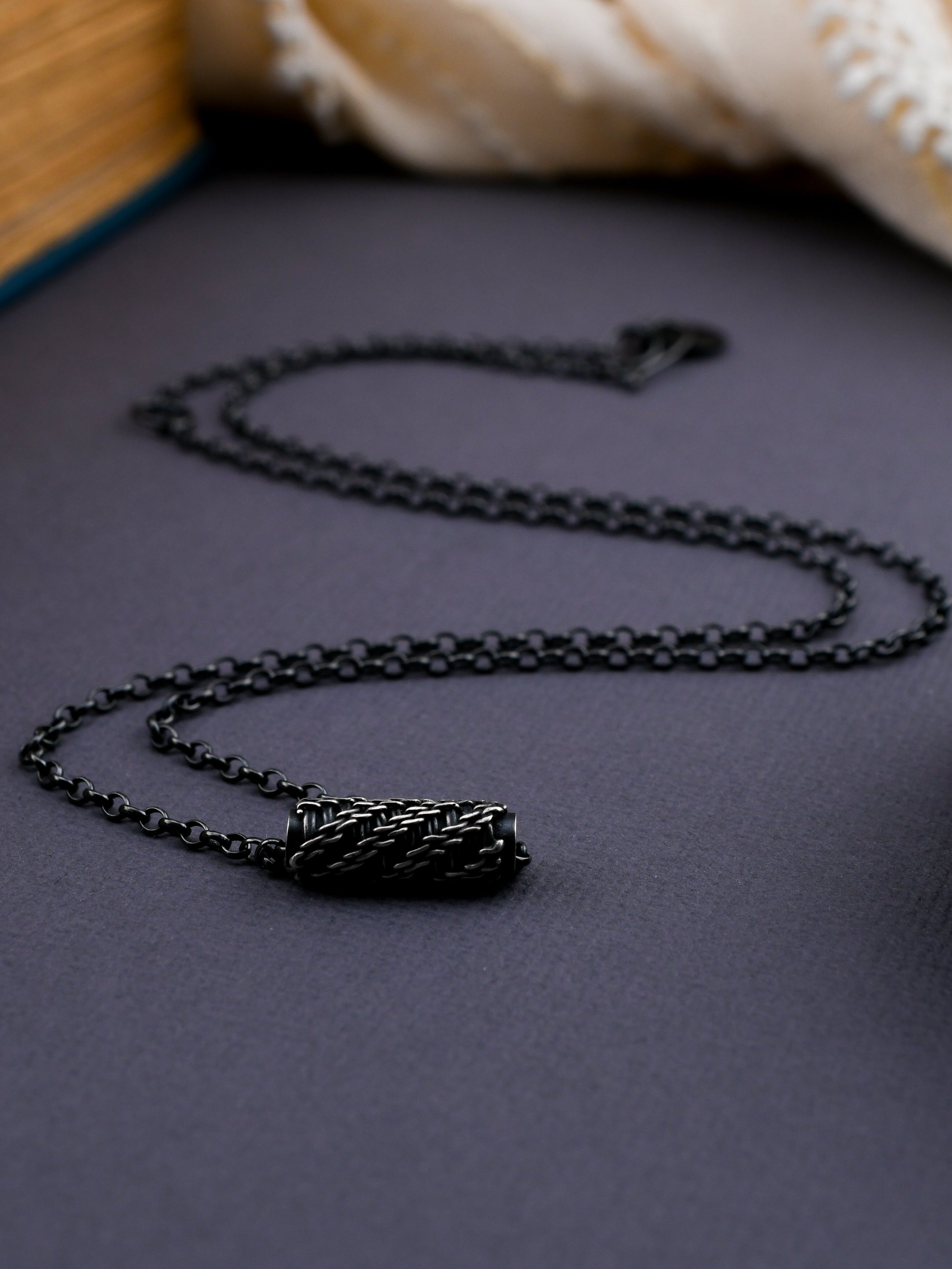 Black woven bead necklace on a textured surface