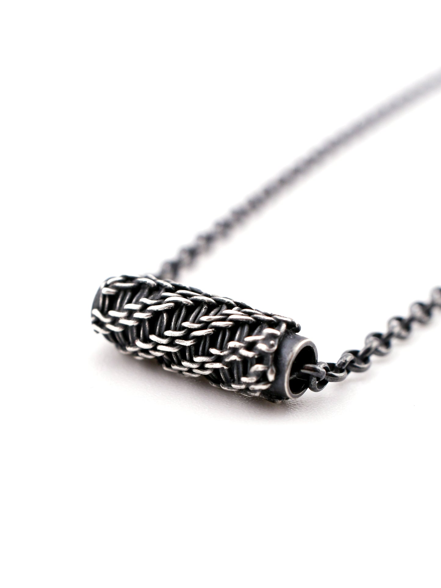 Close-up of a silver necklace with a woven design on a white background
