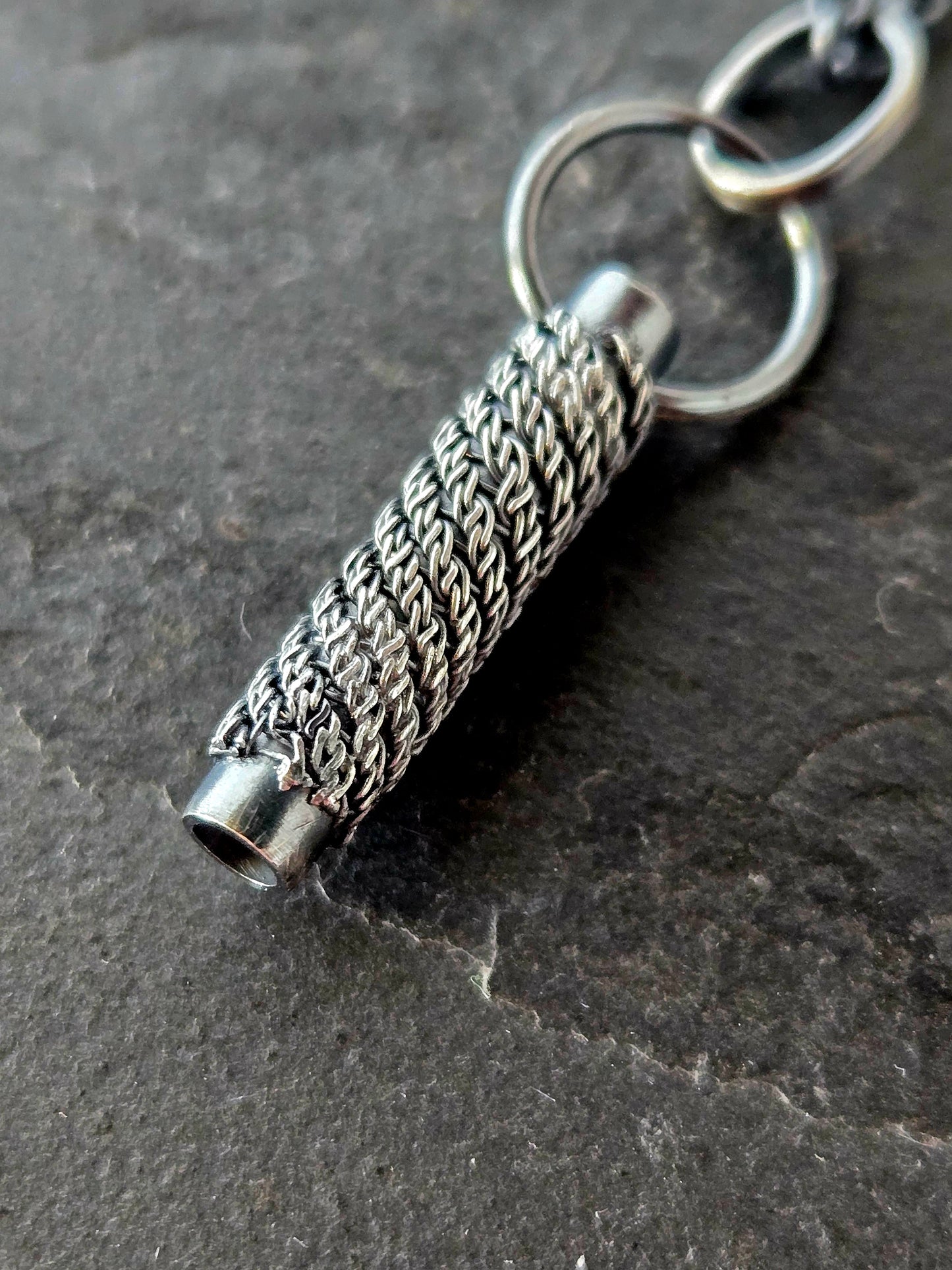 closeup of woven pendant on a textured black background