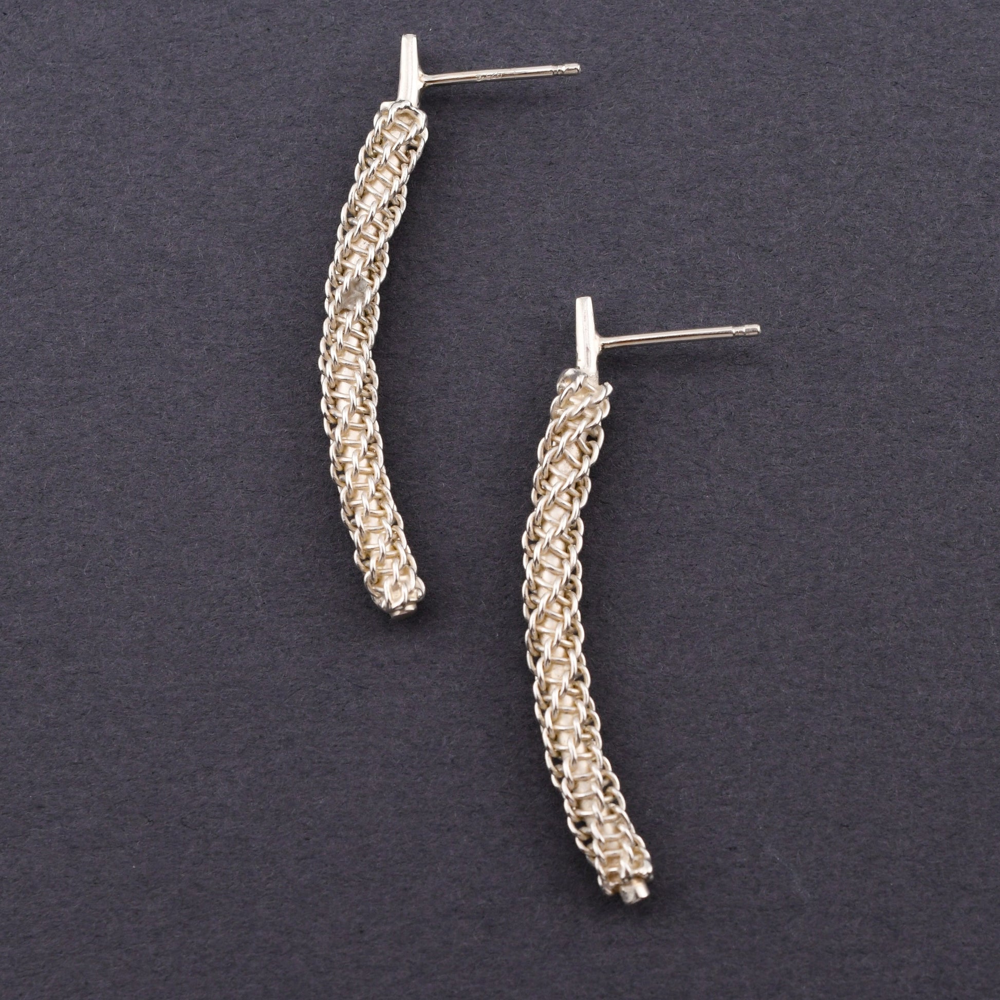 Pair of silver textured earrings on a dark gray background