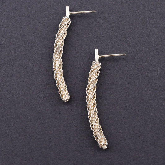 Pair of silver textured earrings on a dark gray background