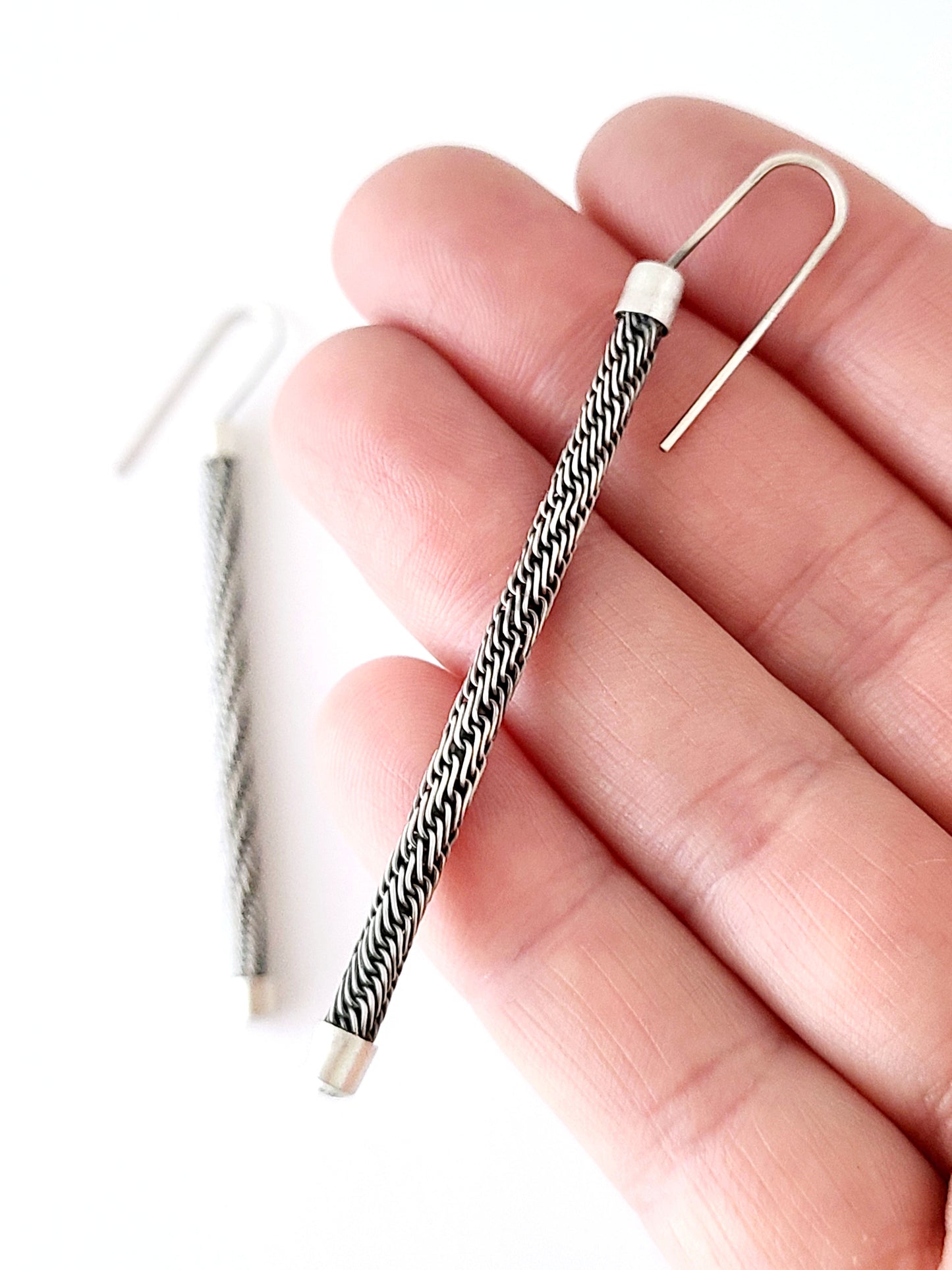Earring with black and white pattern held between fingers on a white background