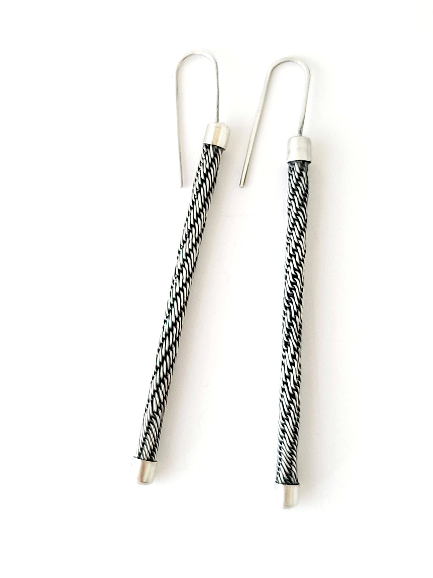 Pair of earrings with black and white patterned wires on a white background