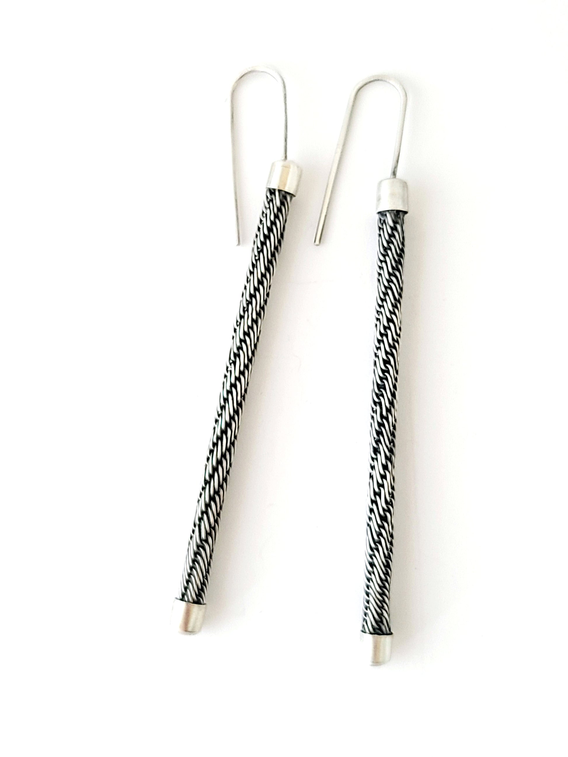 Pair of earrings with black and white patterned wires on a white background
