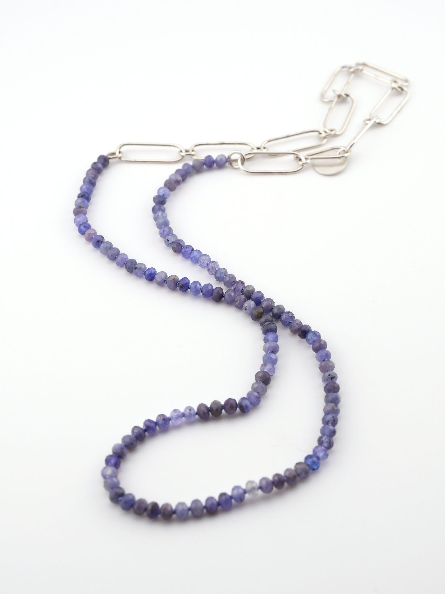 Purple beaded necklace with a silver chain extender on a white background