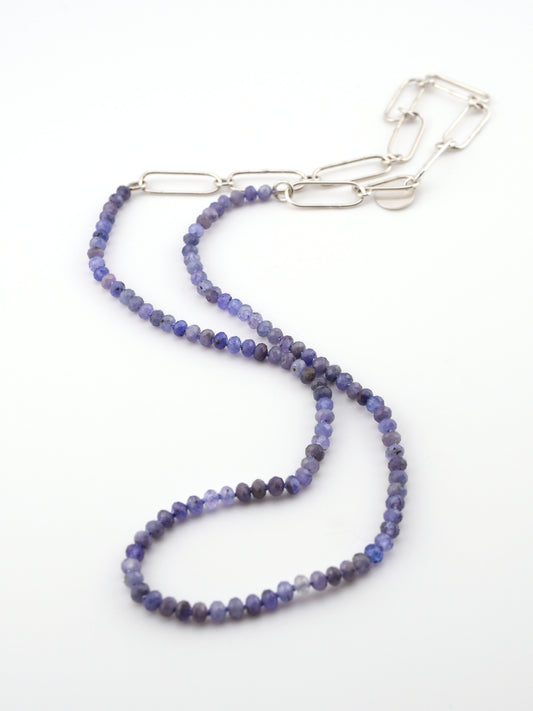 Purple beaded necklace with a silver chain extender on a white background