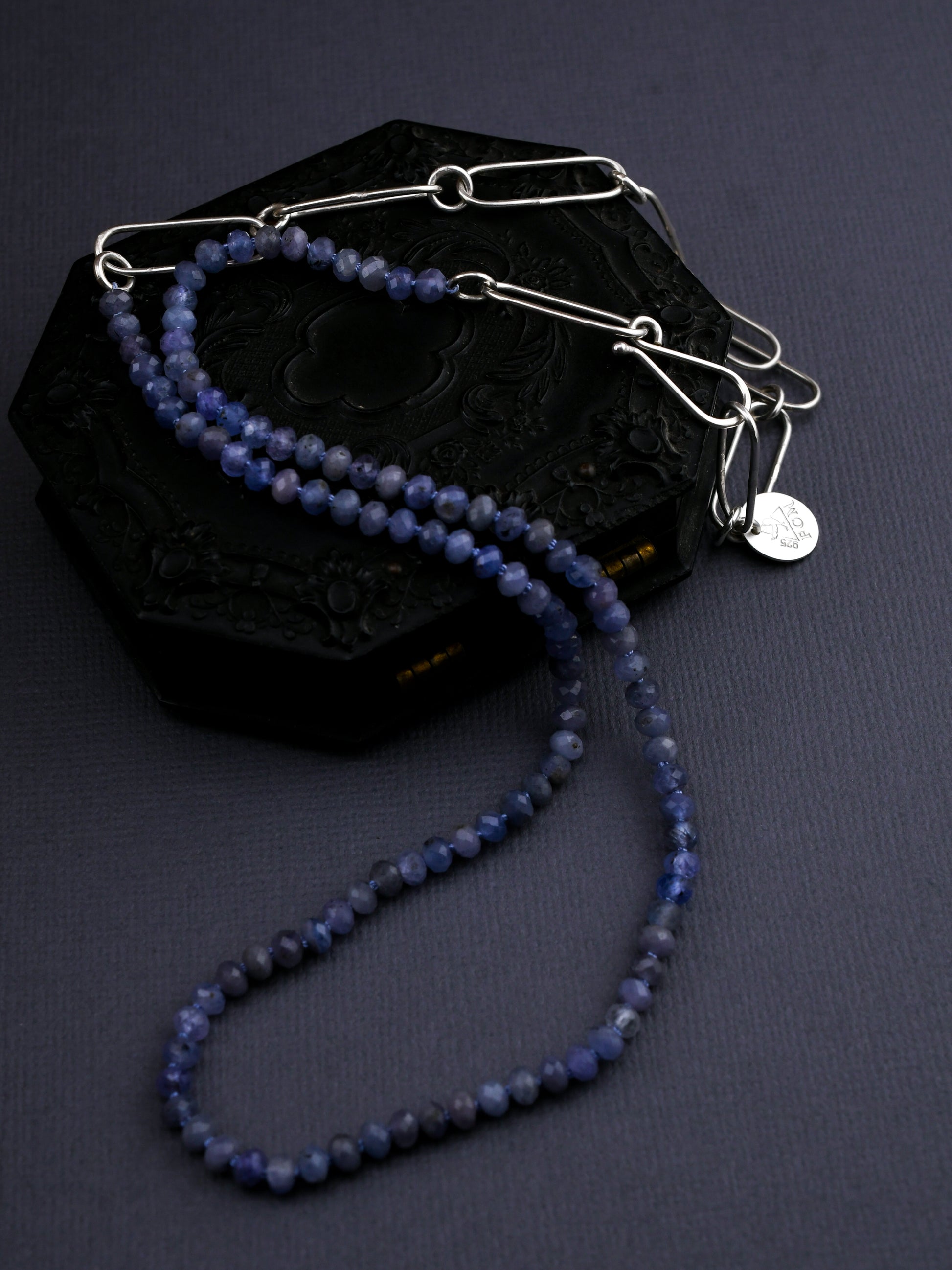 Blue beaded necklace with silver clasp on a dark surface